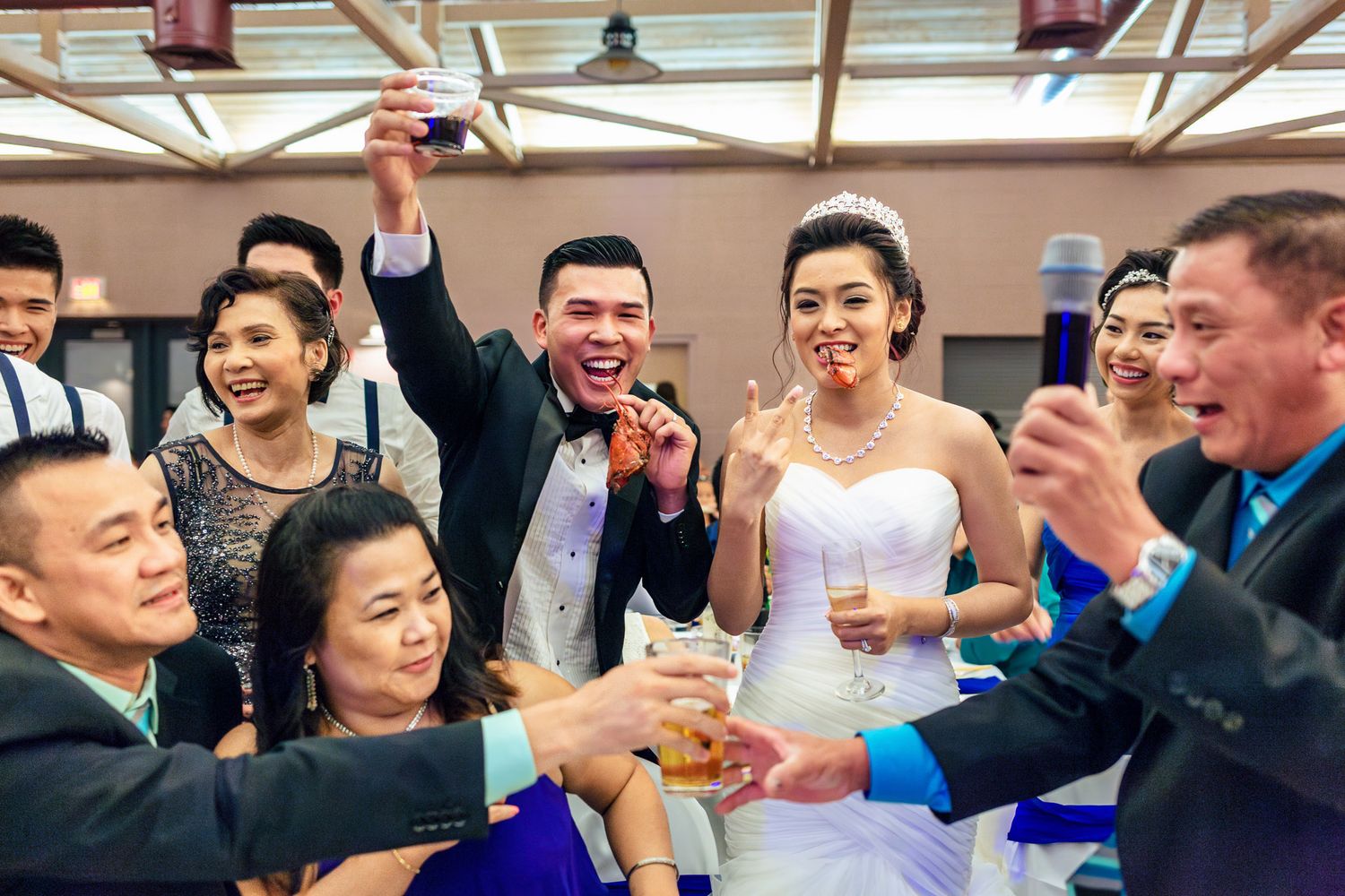Joyful wedding reception toast with bride and groom celebrating with guests holding champagne glasses.