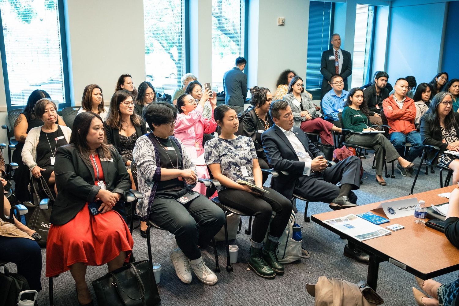 Diverse audience seated in rows at an indoor conference or community event in a modern meeting room.