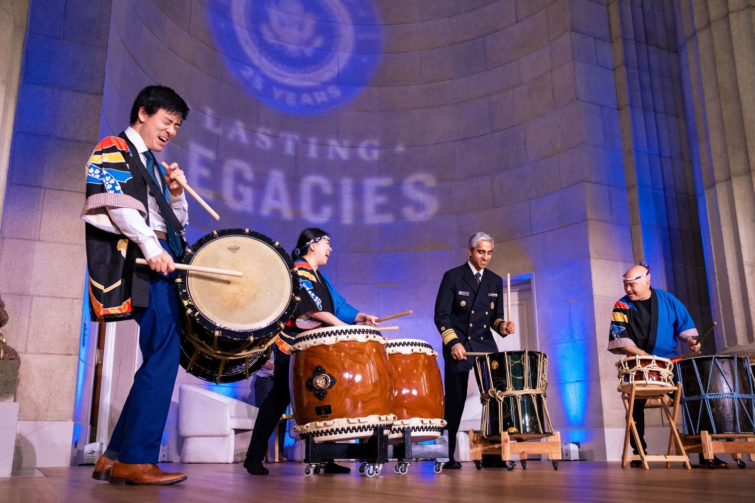 Four performers play traditional taiko drums on stage at a Lasting Legacies ceremony event.