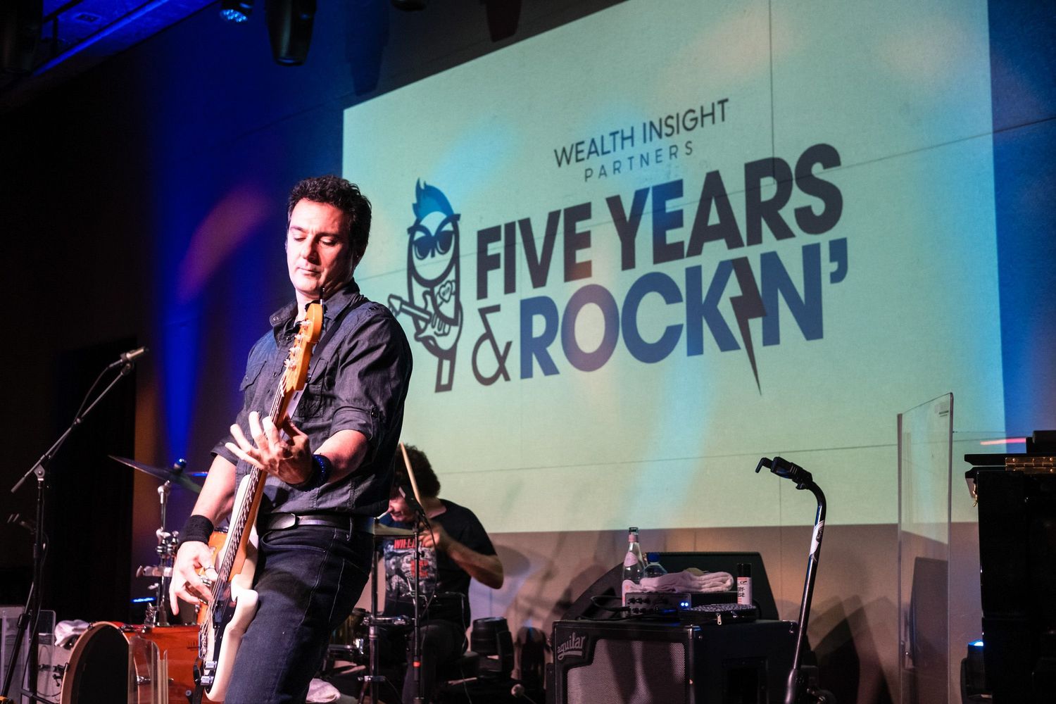 Guitarist performs on stage at Wealth Insight Partners Five Years and Rockin' anniversary celebration event.