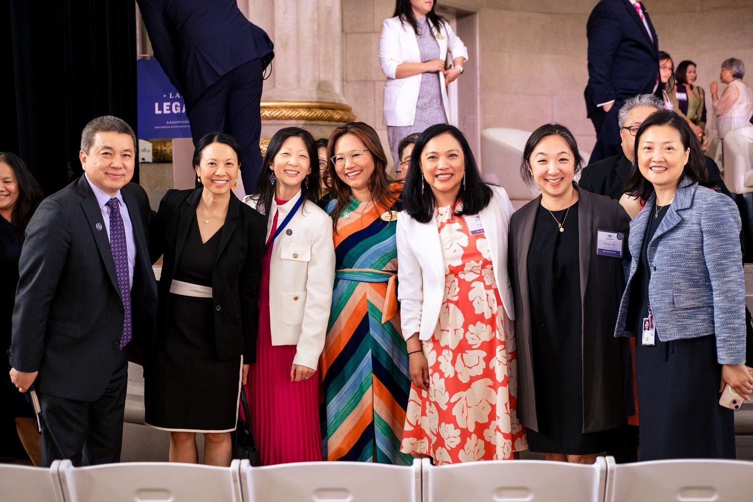 Group of seven professionals posing together at a formal event in an elegant venue.