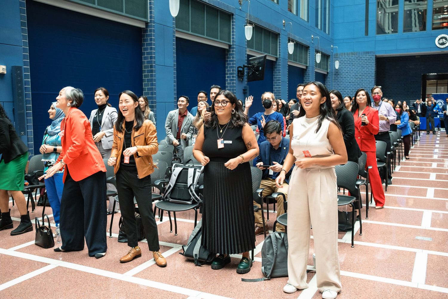 Diverse group of people standing and socializing at an indoor event in a brick-walled venue.