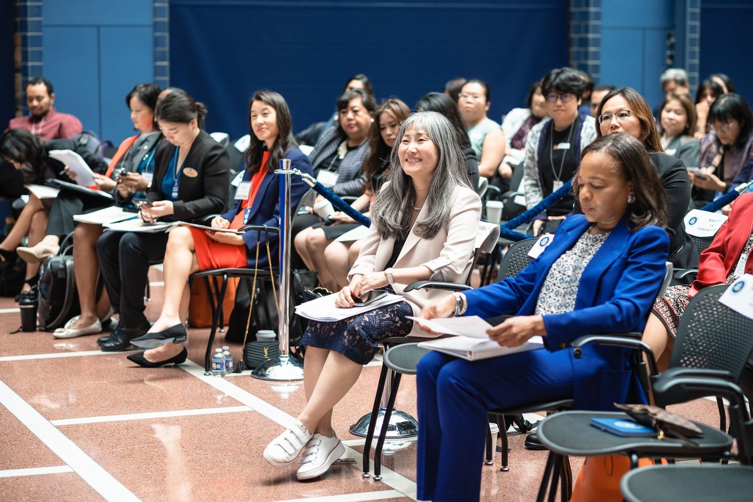 Diverse group of attendees seated and engaged during a professional policy summit conference session.