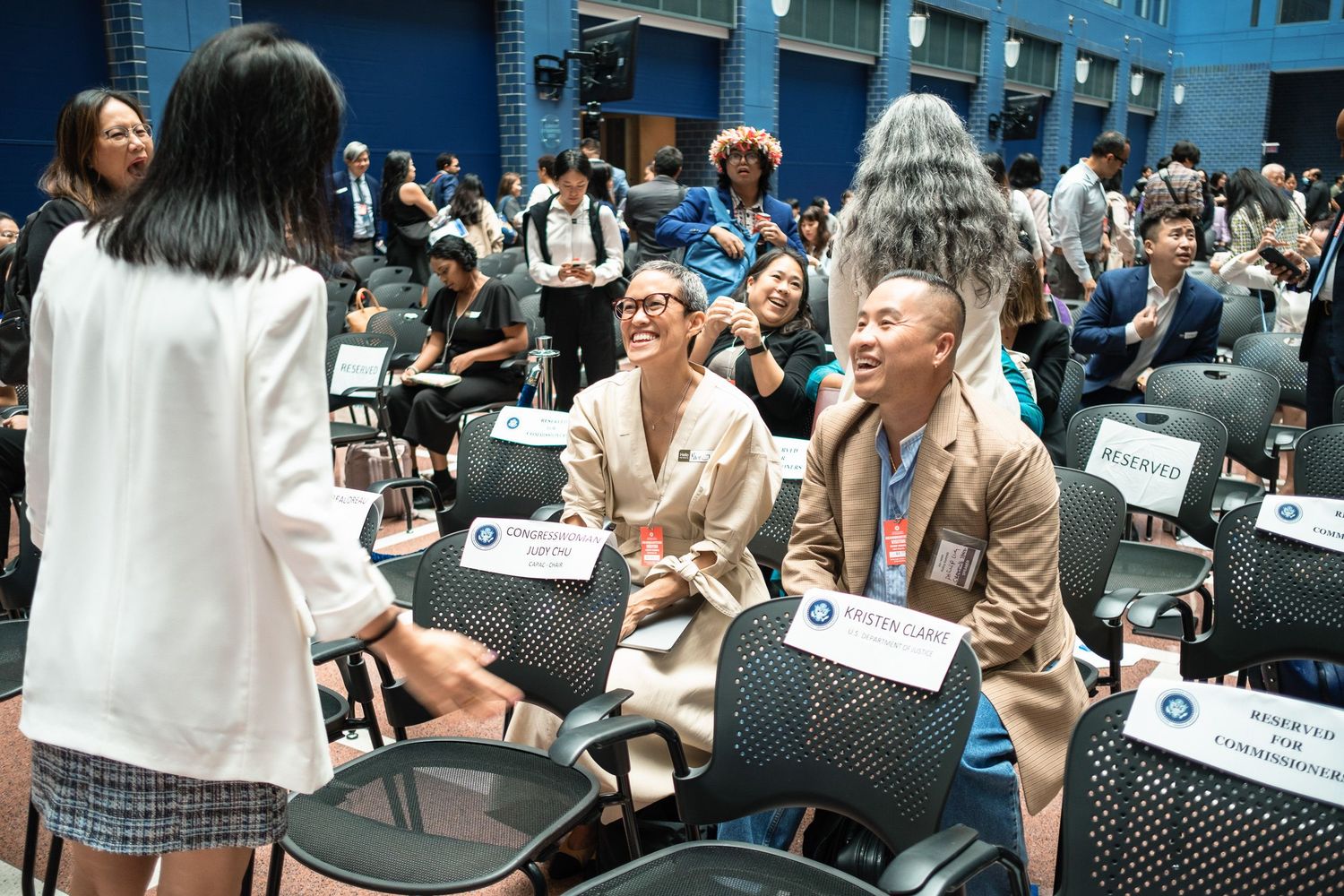 Attendees networking and conversing cheerfully between chairs at a professional government conference event.