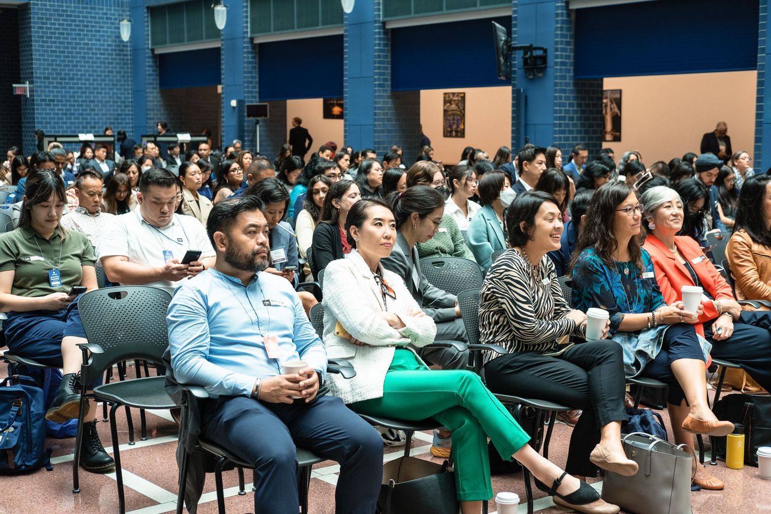 Large audience seated in auditorium attentively watching a presentation at a professional conference event.