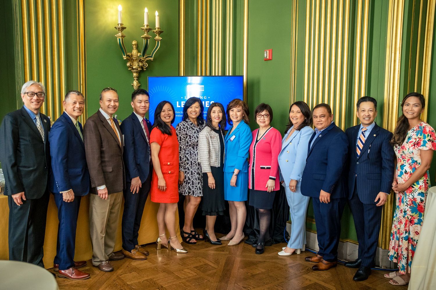 Group of professionals posing together in an elegant green-walled room at a formal event.