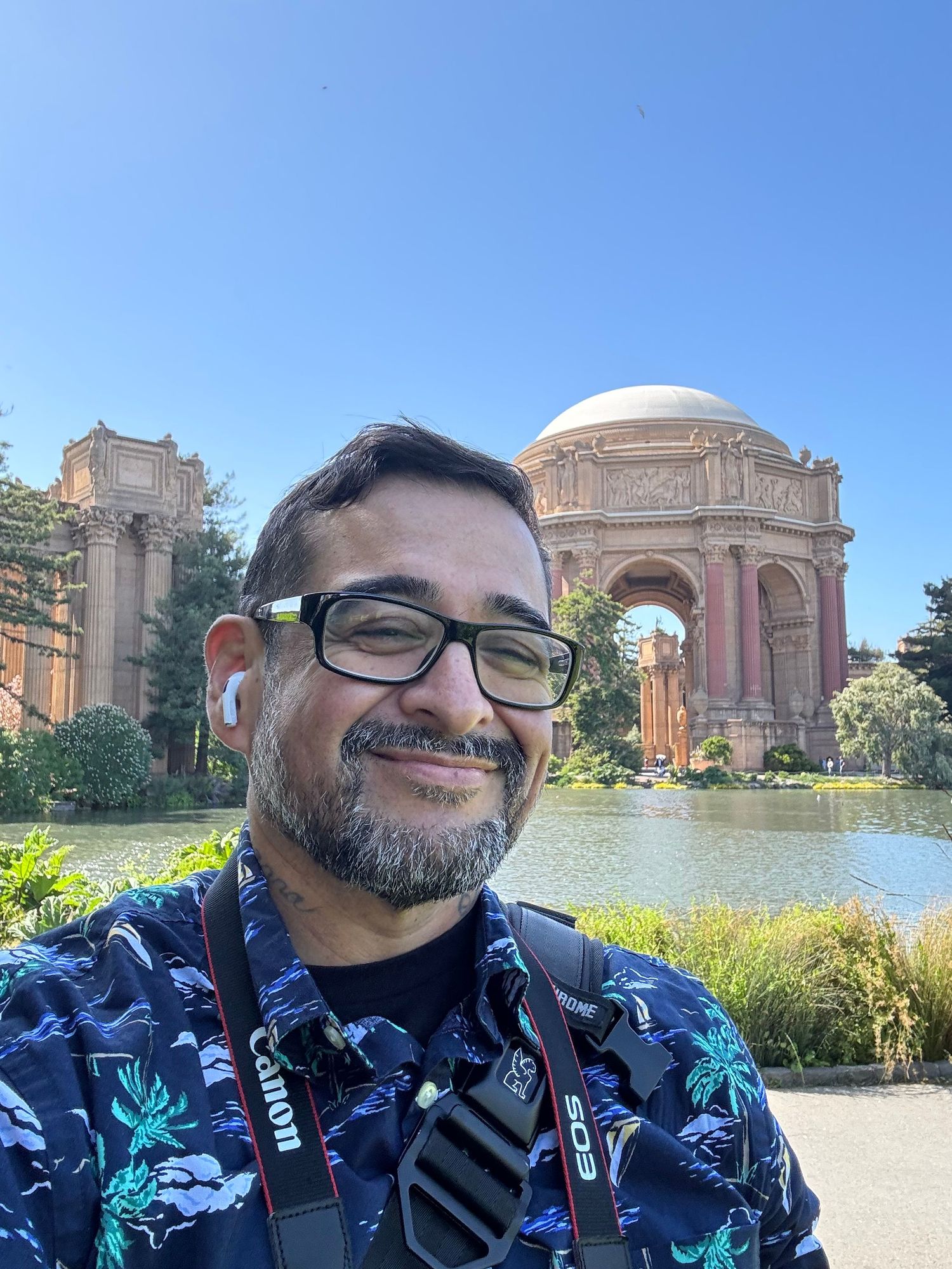 Man with glasses and camera at Palace of Fine Arts, San Francisco, on a sunny day.