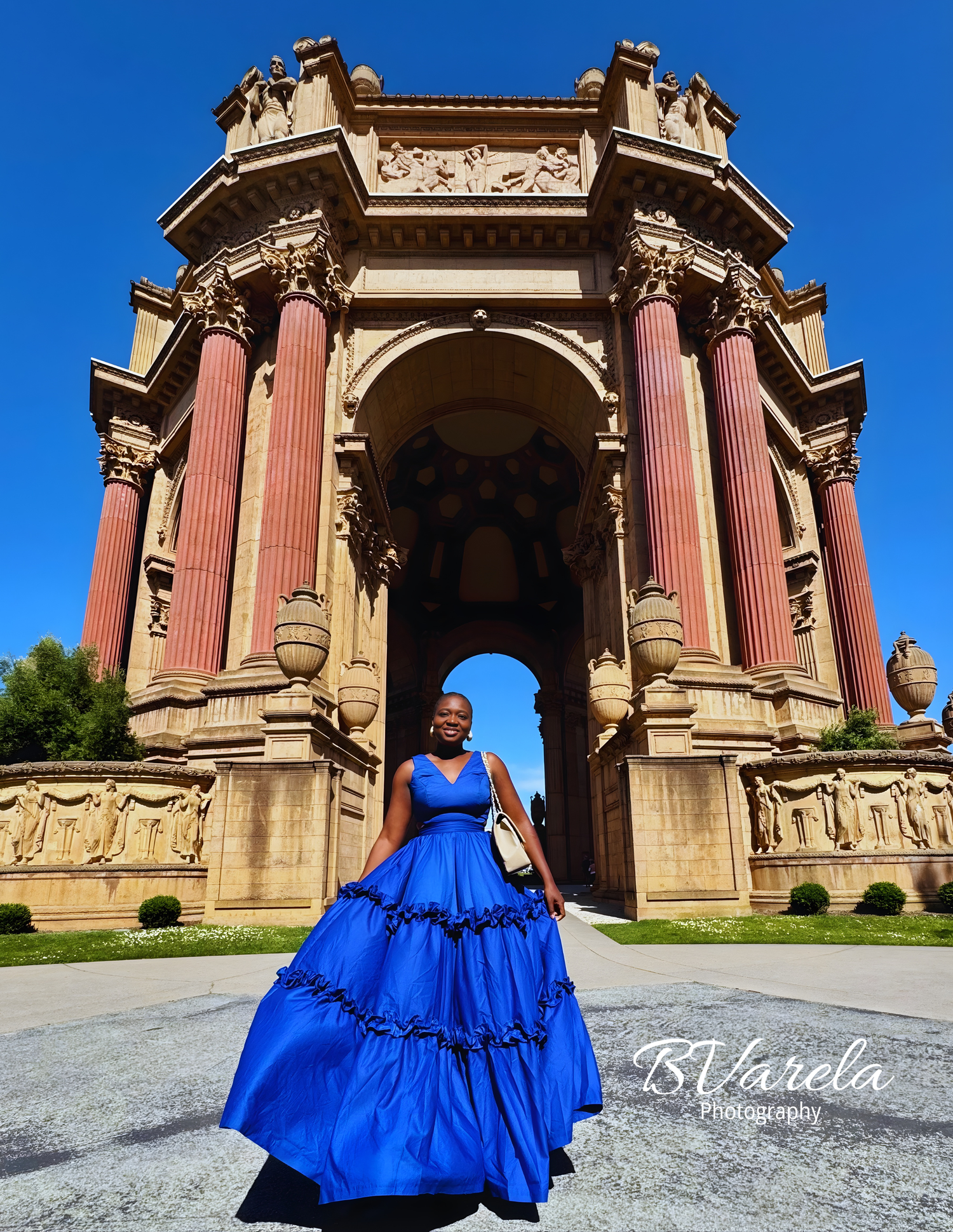 Woman in royal blue ballgown poses before the Palace of Fine Arts rotunda columns in San Francisco.