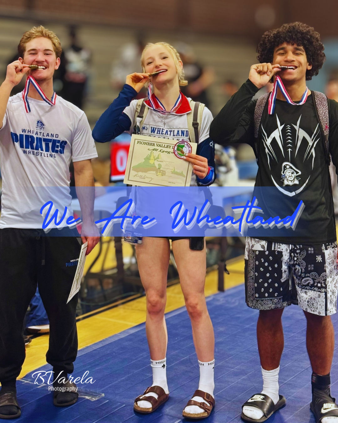 Three Wheatland Pirates wrestlers proudly display gold medals at a wrestling tournament, smiling on a blue mat.