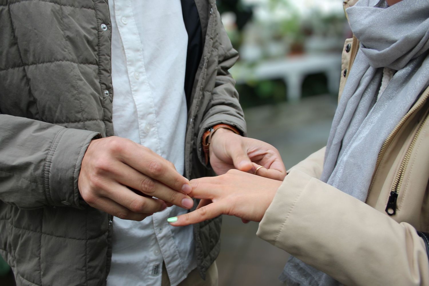 Close-up of a couple exchanging a ring outdoors, symbolizing a romantic proposal or engagement ceremony.