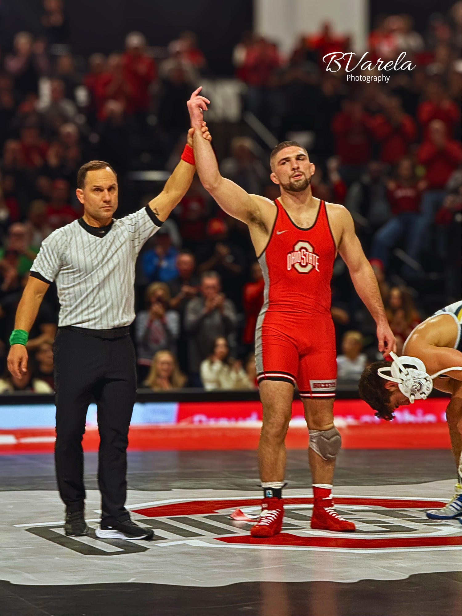 Ohio State wrestler wins match as referee raises his hand in victory on the mat. sport photographer
