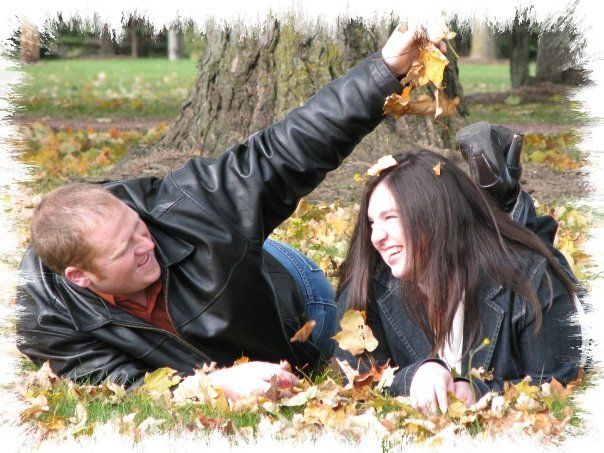 engaged couple lying in fall leaves playing around