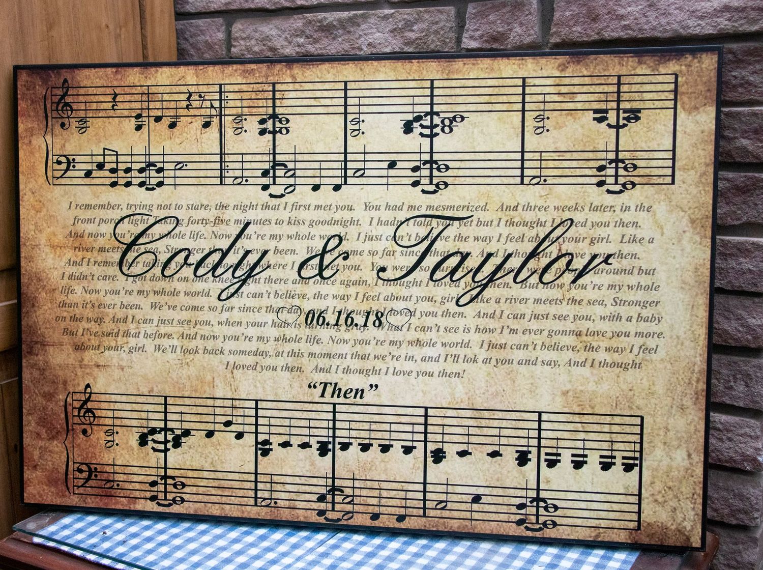 A canvas displaying a bride and groom's name with the words of their first dance song and bars of music