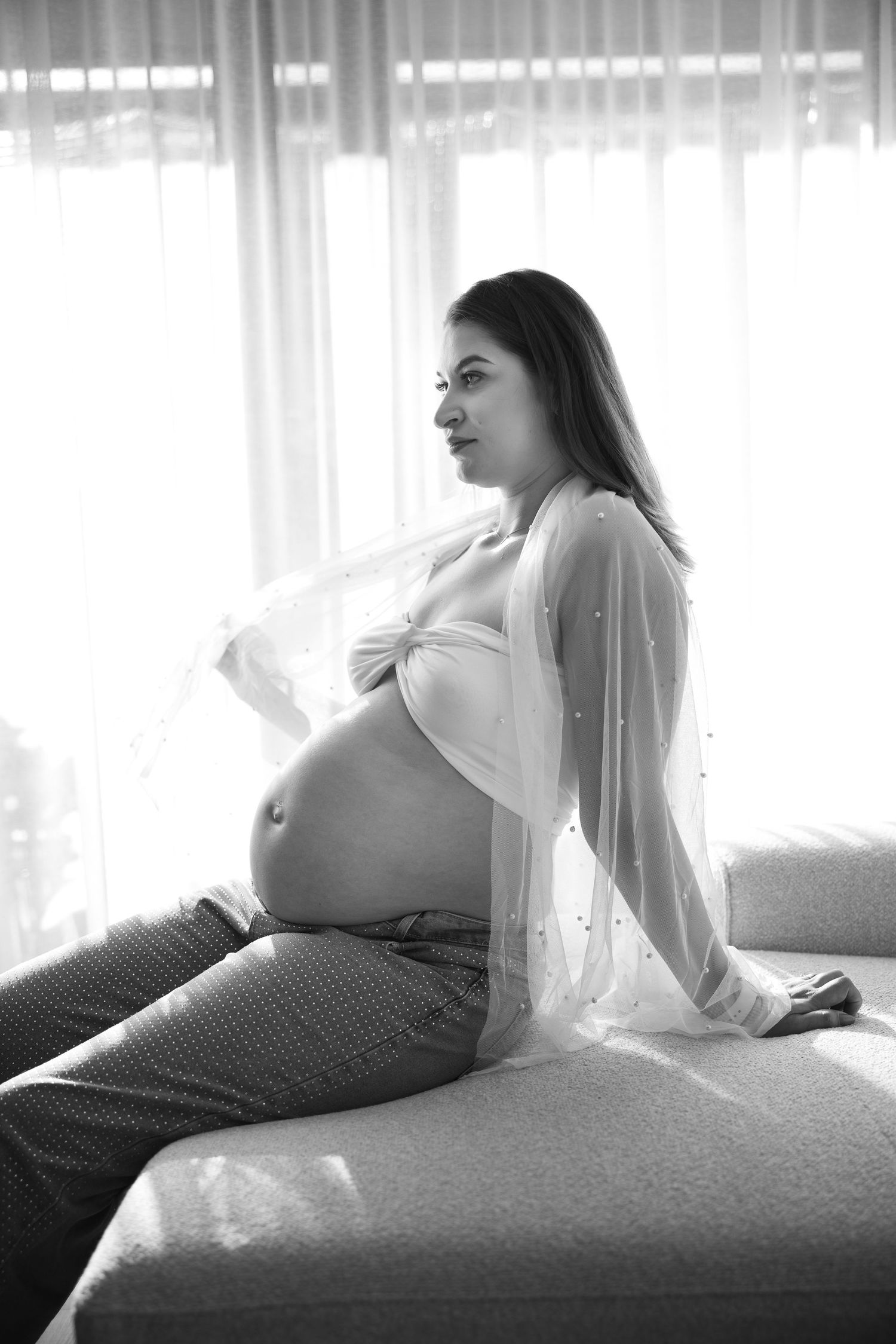 Black and white sunlit portrait of a pregnant woman during an at-home pregnancy photoshoot in Amsterdam