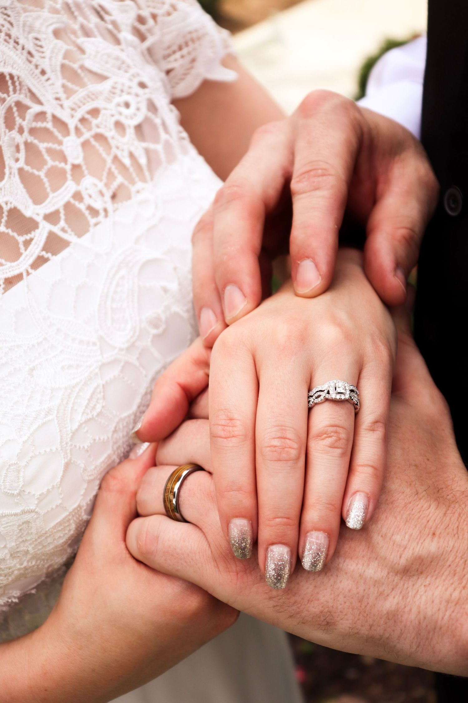 Close-up sequence of hands with wedding rings showing romantic finger interlock gestures against white lace background.