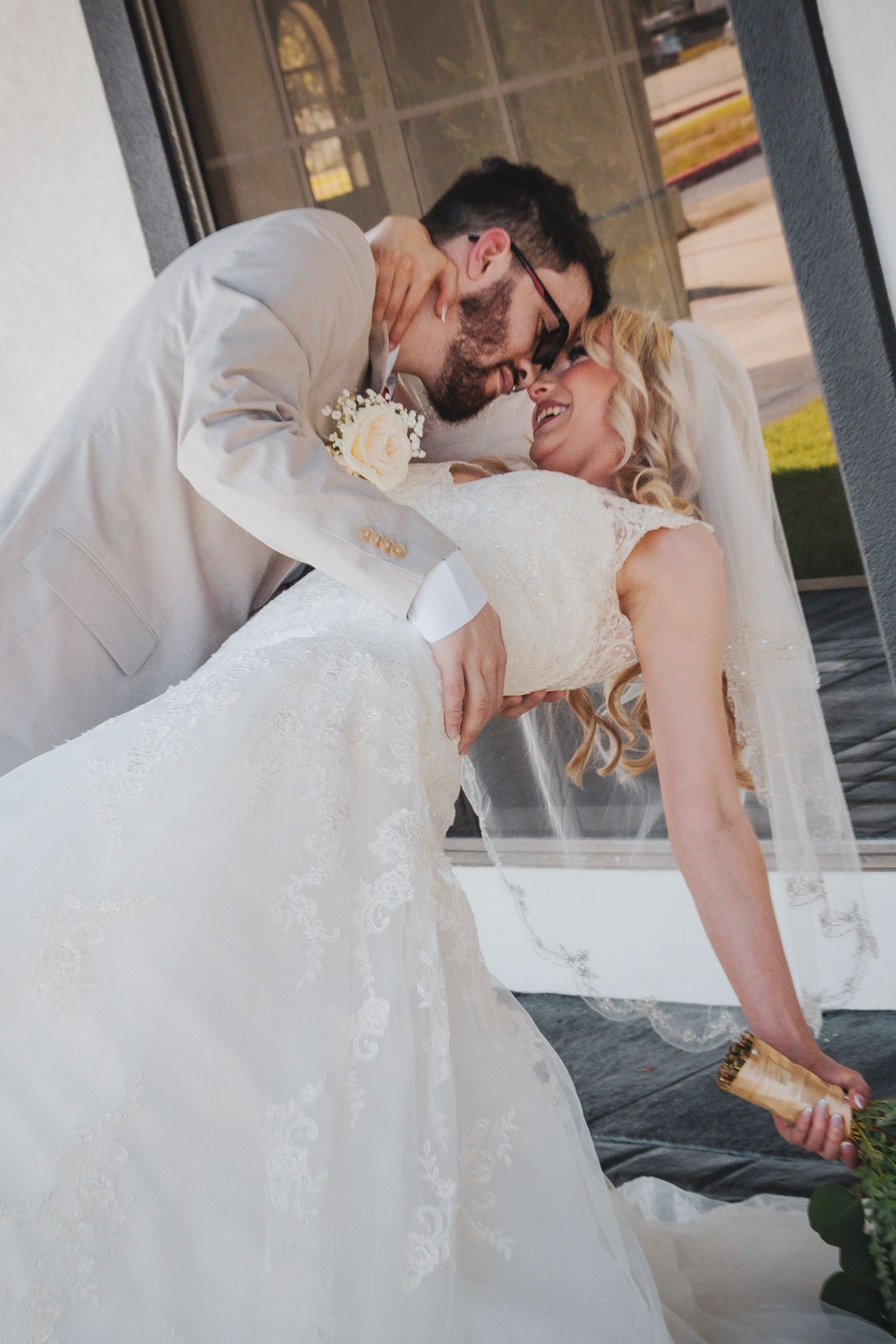 A romantic wedding couple shares a passionate dip kiss while the bride's white dress flows elegantly around them.