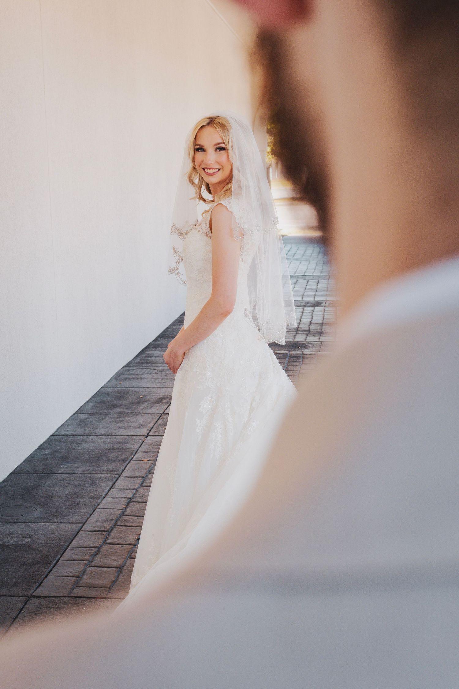 A bride in a flowing white wedding dress poses gracefully on a stone patio during a romantic photoshoot.