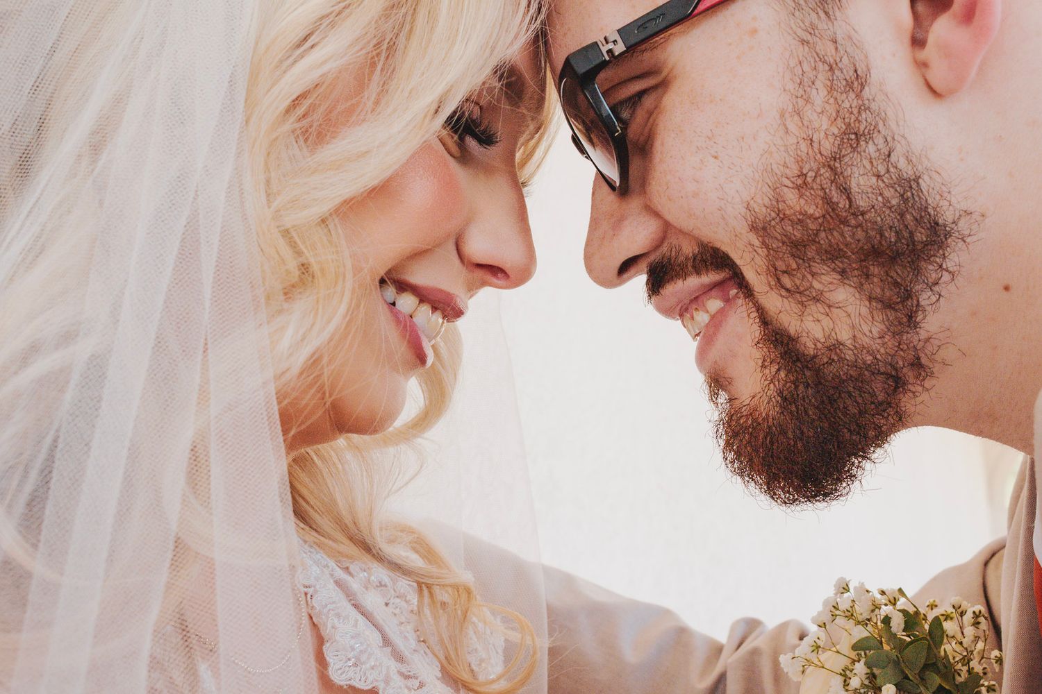 A romantic close-up side profile of a couple in wedding attire sharing an intimate moment together.