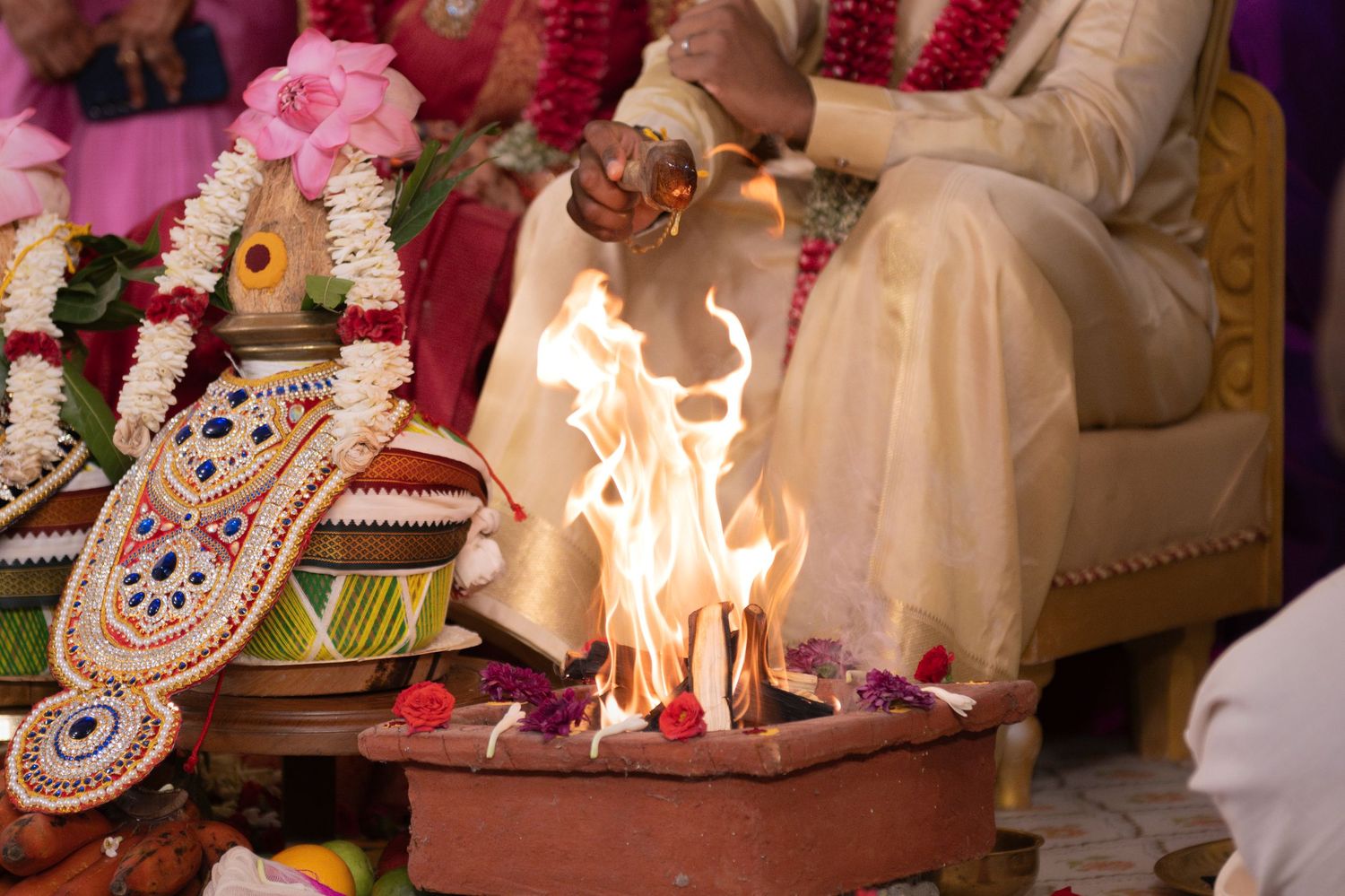 A flame is lit for the Lajja Homam, the bride and groom are seated in the background.