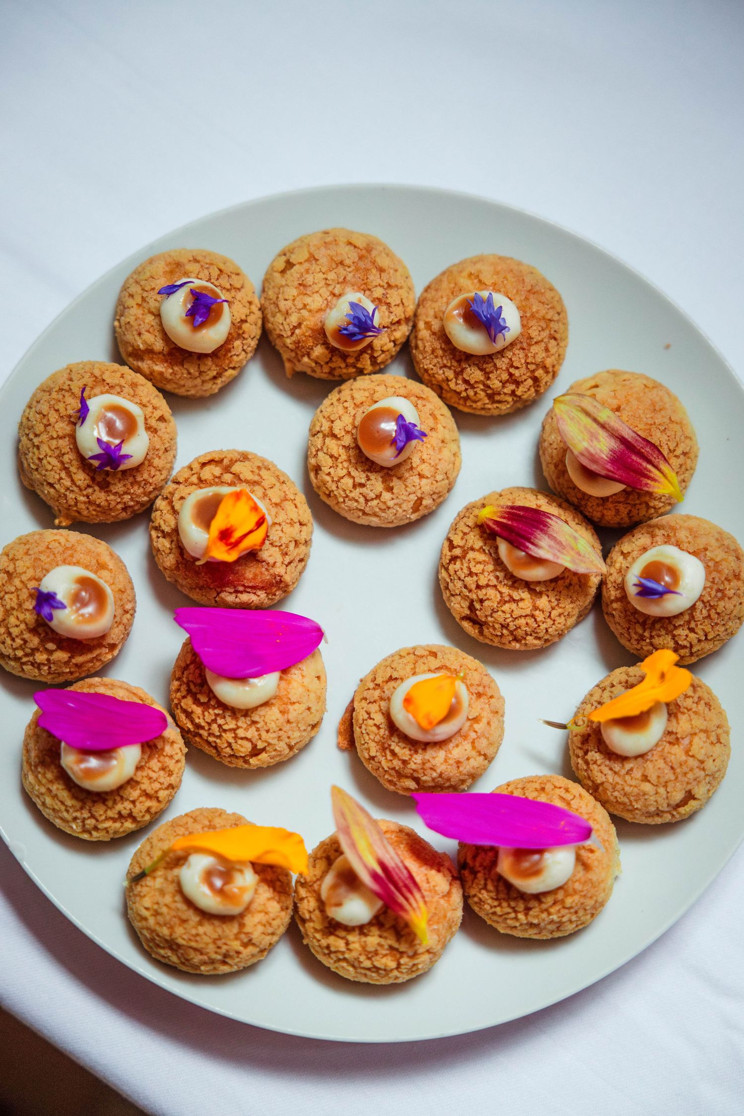 Elegant plate of decorated cookies topped with edible flowers and cream.