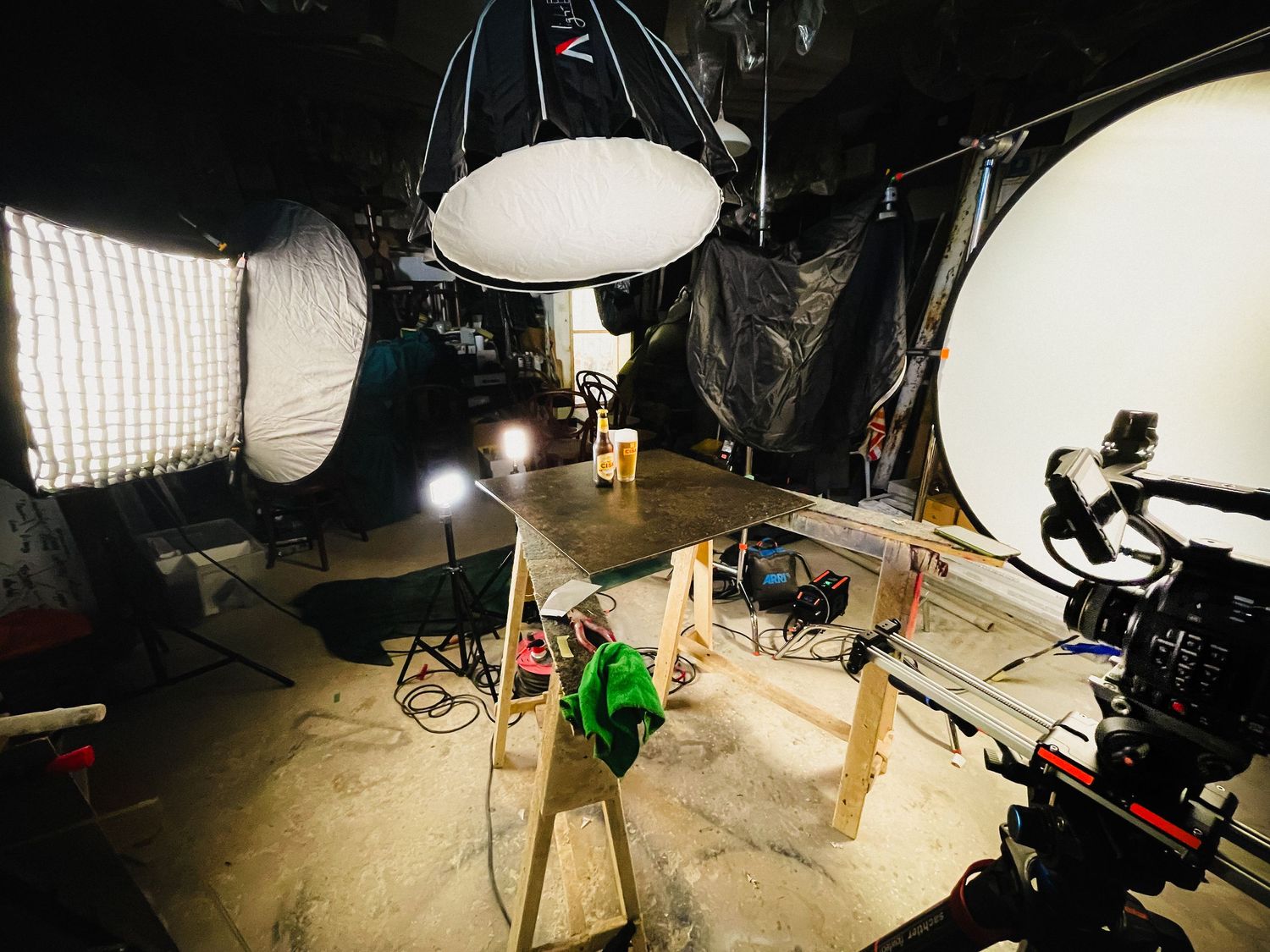 Professional video production set with multiple lights and camera equipment arranged around a small tabletop product photography setup.
