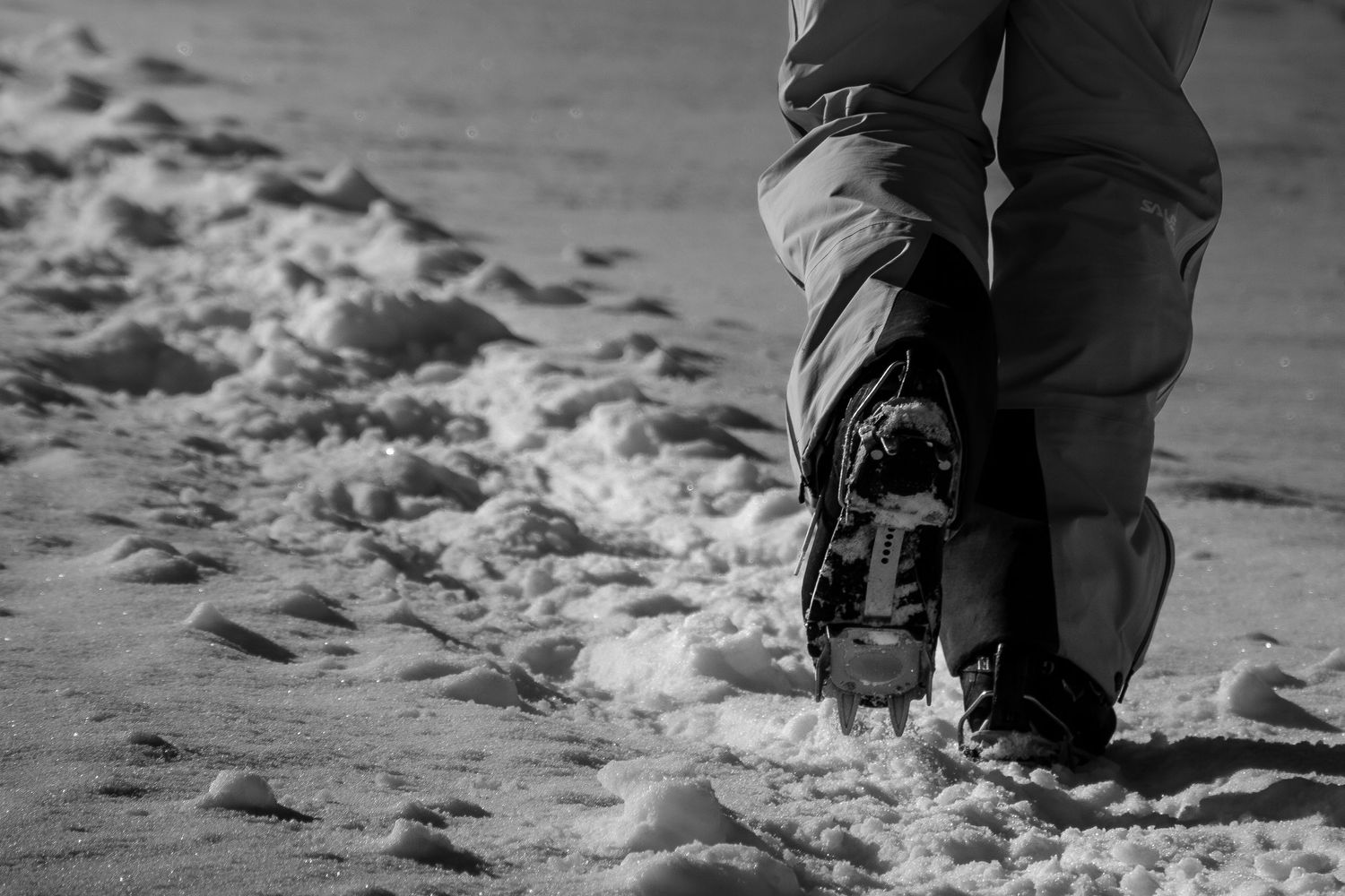 Close-up of boots walking through fresh snow in black and white.