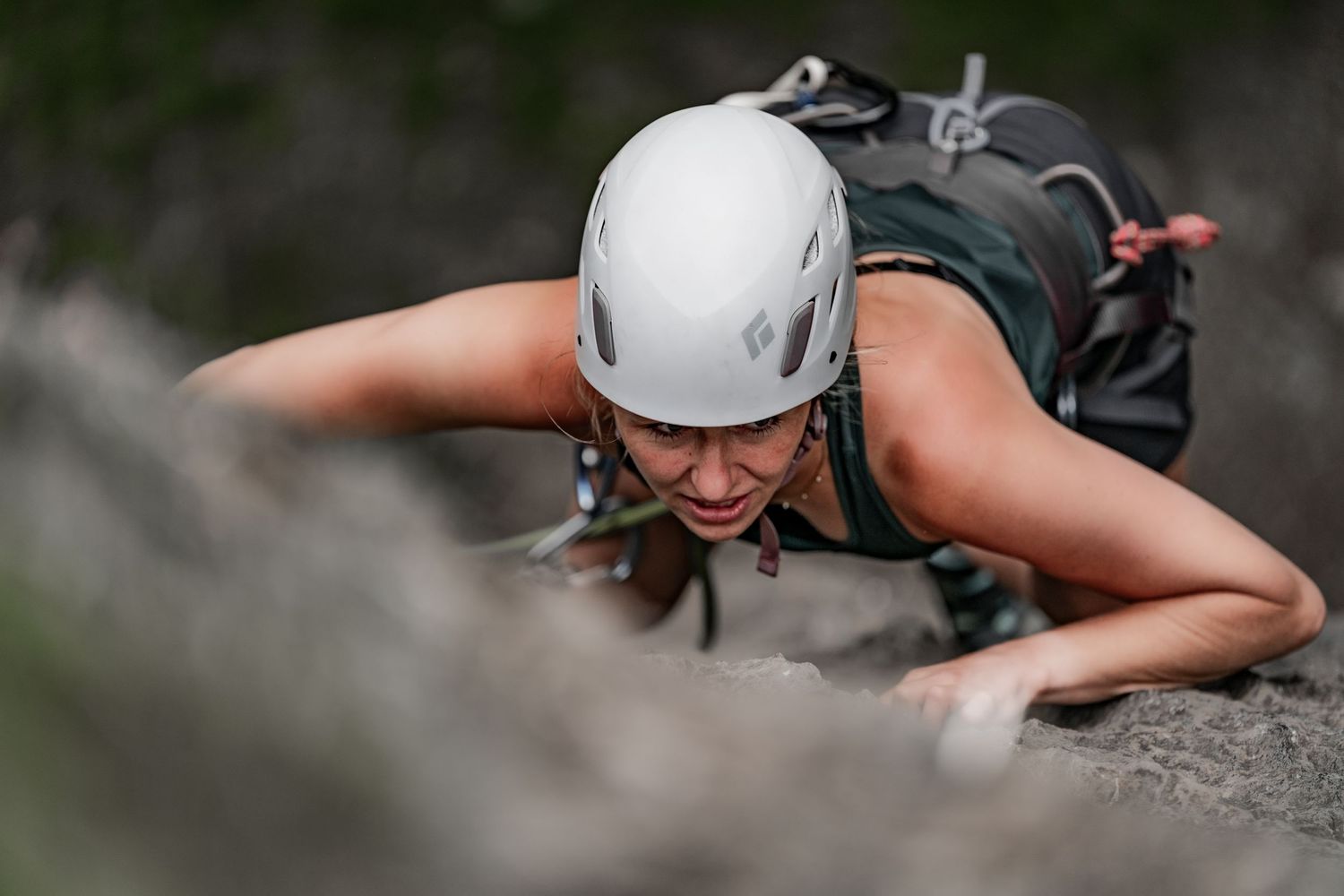 Rock climber in white helmet focused on ascending steep cliff face.