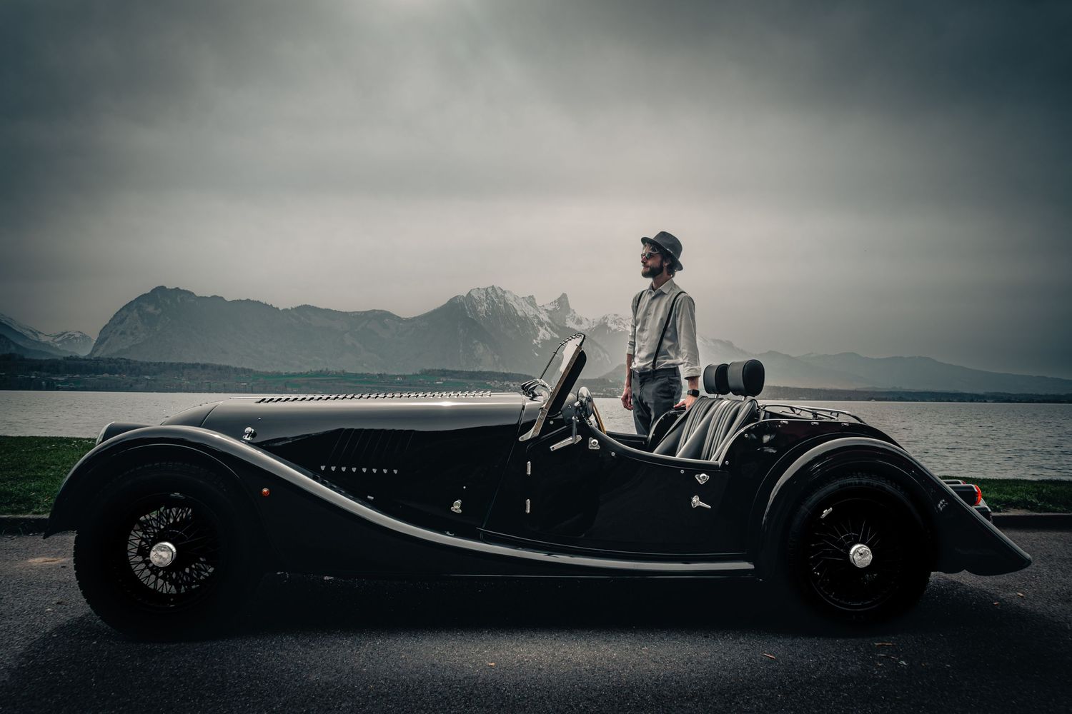 Vintage black classic car parked along a scenic mountain road.