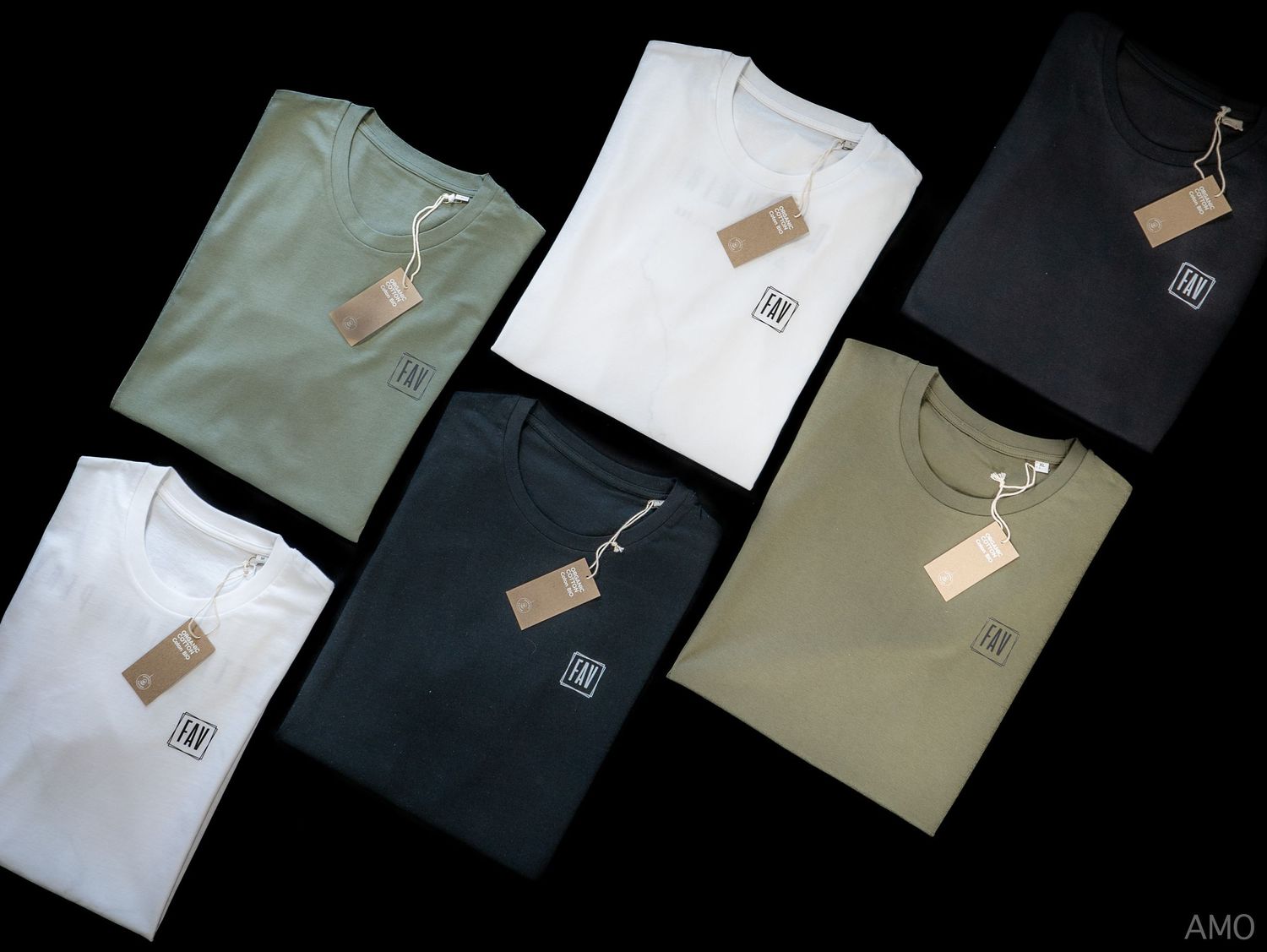 Flat lay of six t-shirts in various earth tones arranged neatly on a black background.
