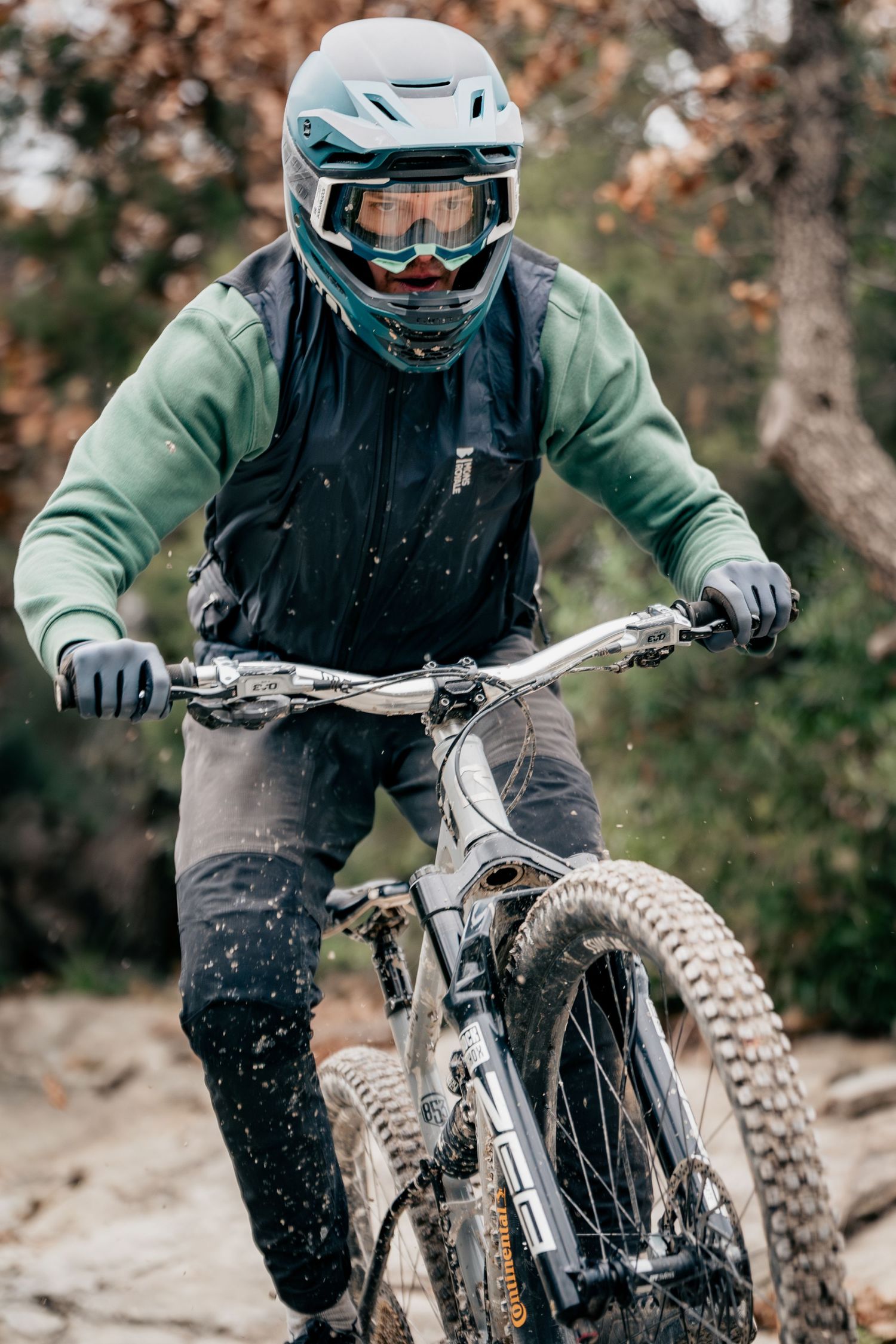 Mountain biker in protective gear navigating rocky terrain in natural setting.
