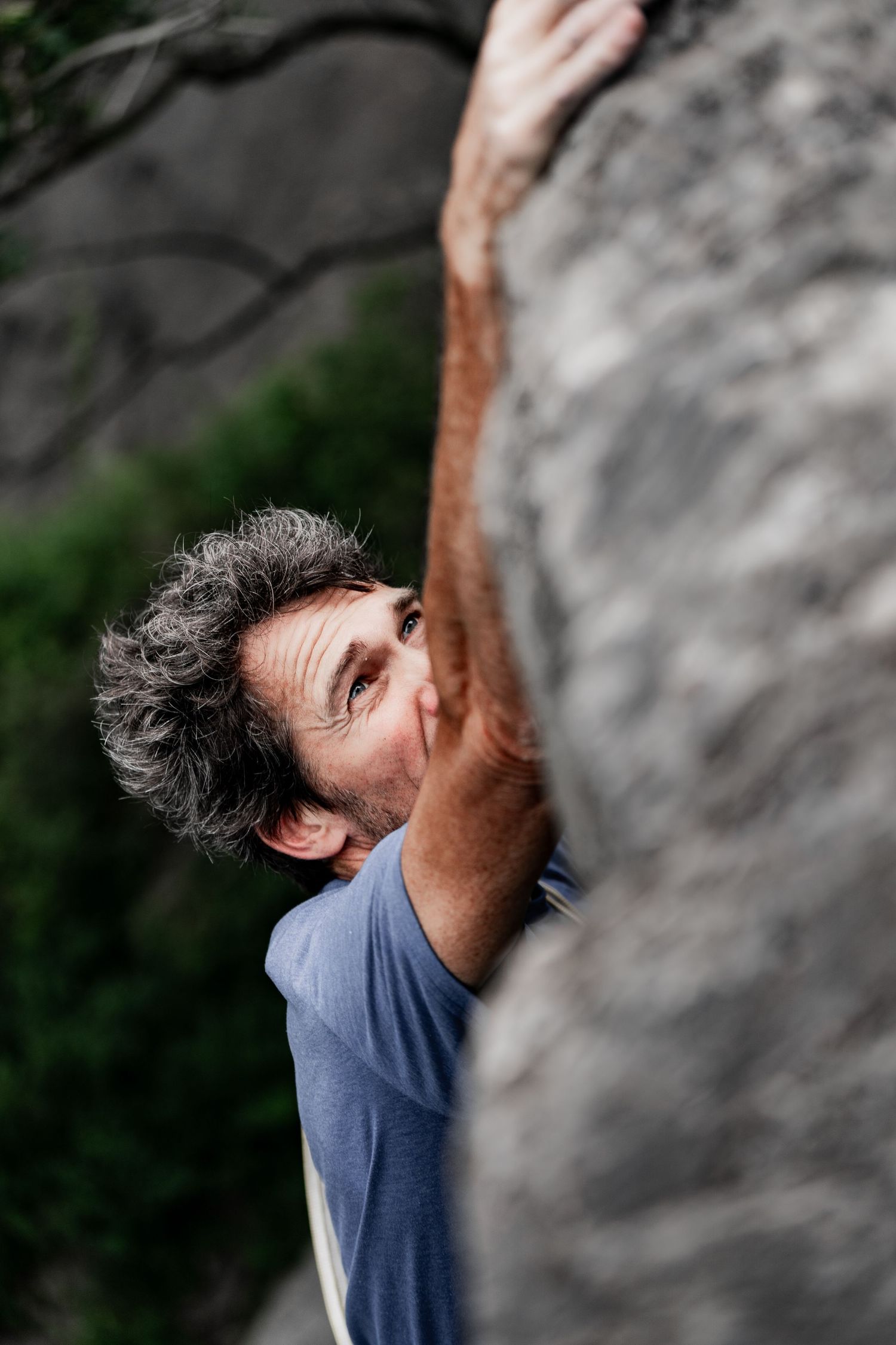 Rock climber reaching for next hold while scaling natural cliff wall.