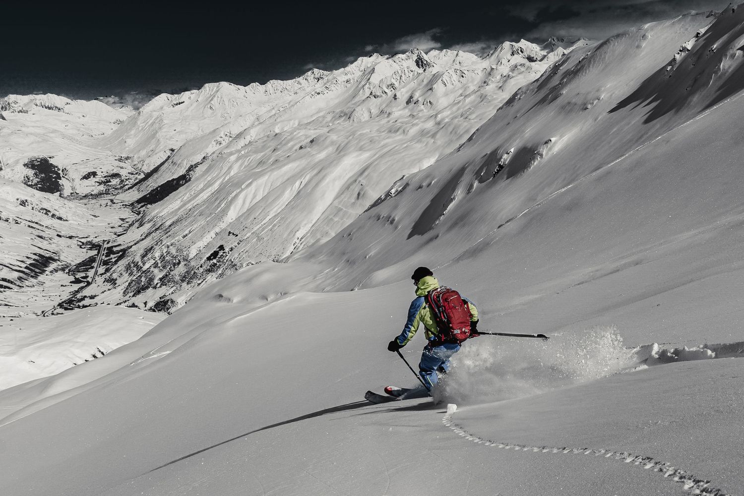 Skier carving through fresh powder snow on a steep mountain slope.