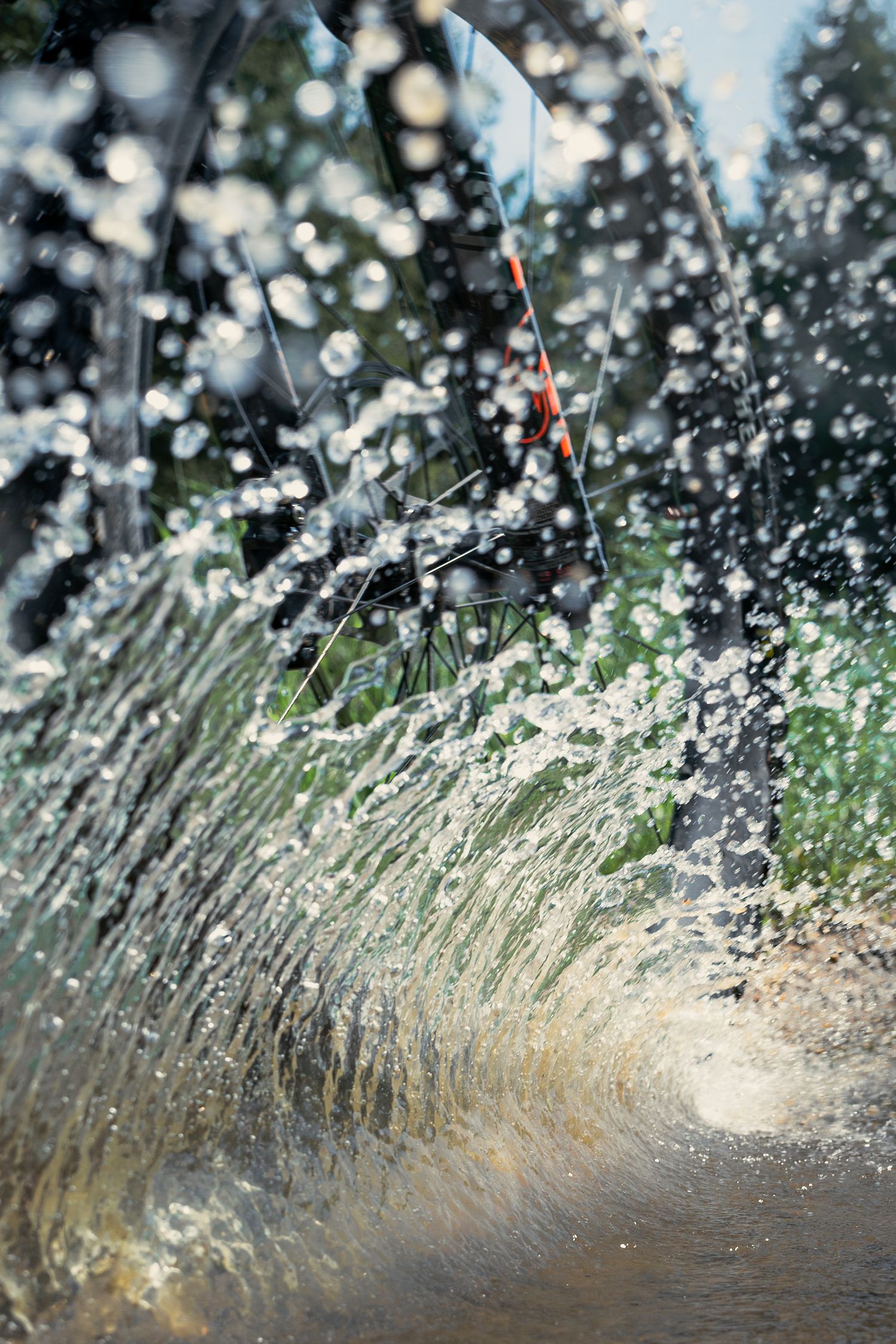 Water splashing and spraying against blurred nature background on mountain bike trail.