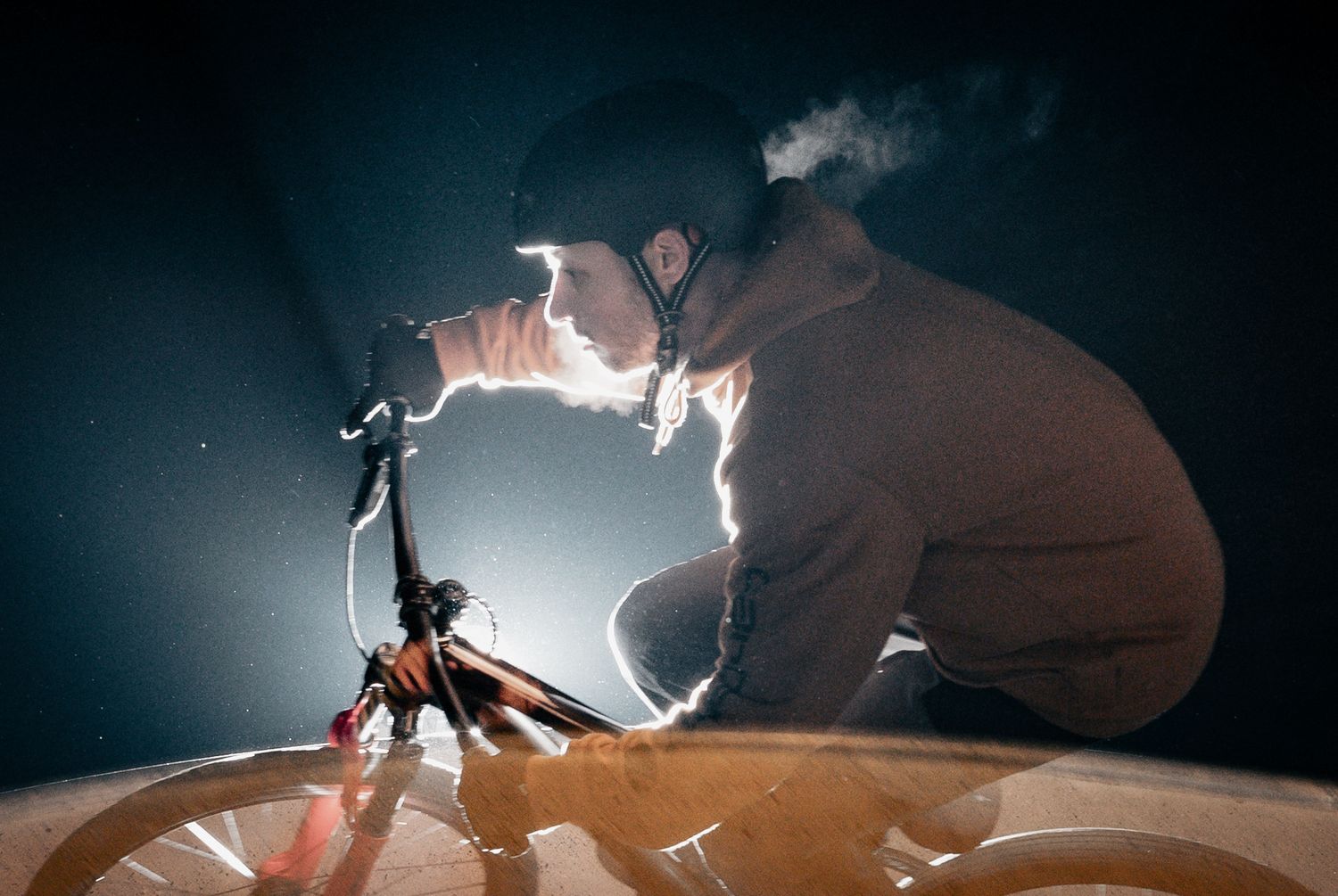 Photographer illuminating a bike with a flashlight in dark setting creating dramatic lighting effects and shadows.