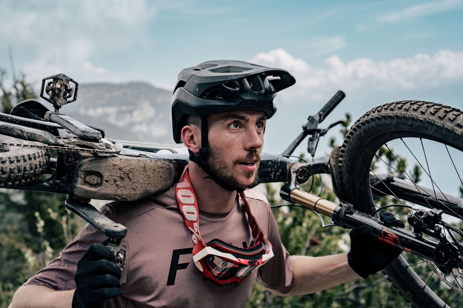 Mountain biker carrying bicycle on shoulder during outdoor adventure.