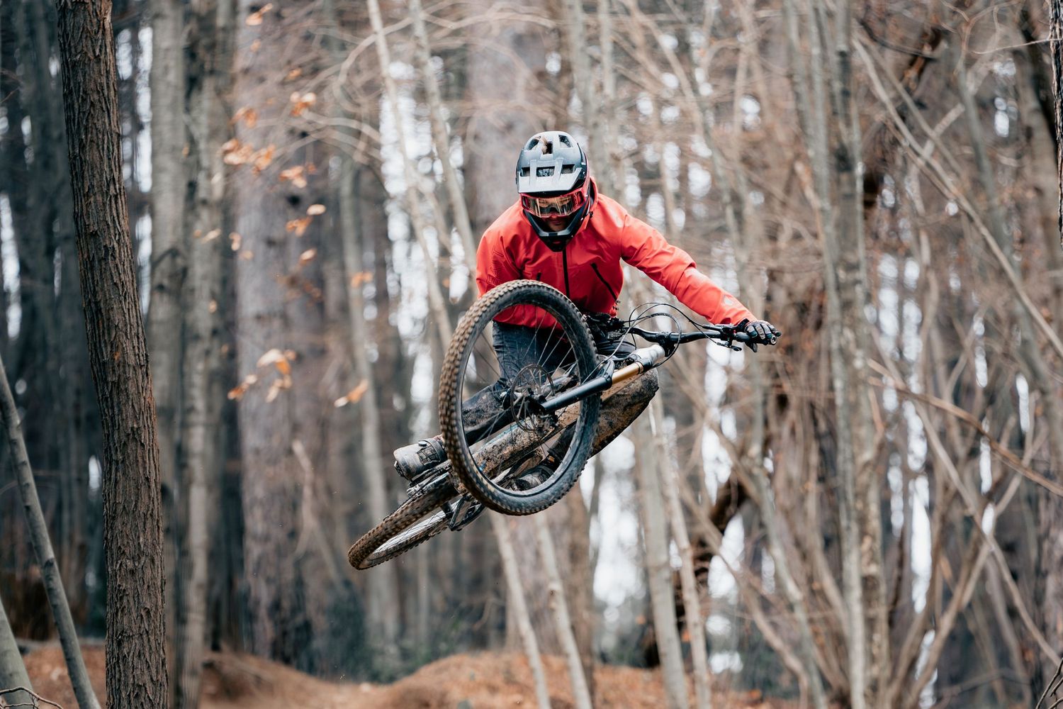 Mountain biker executing stylish tabletop between bare winter trees.
