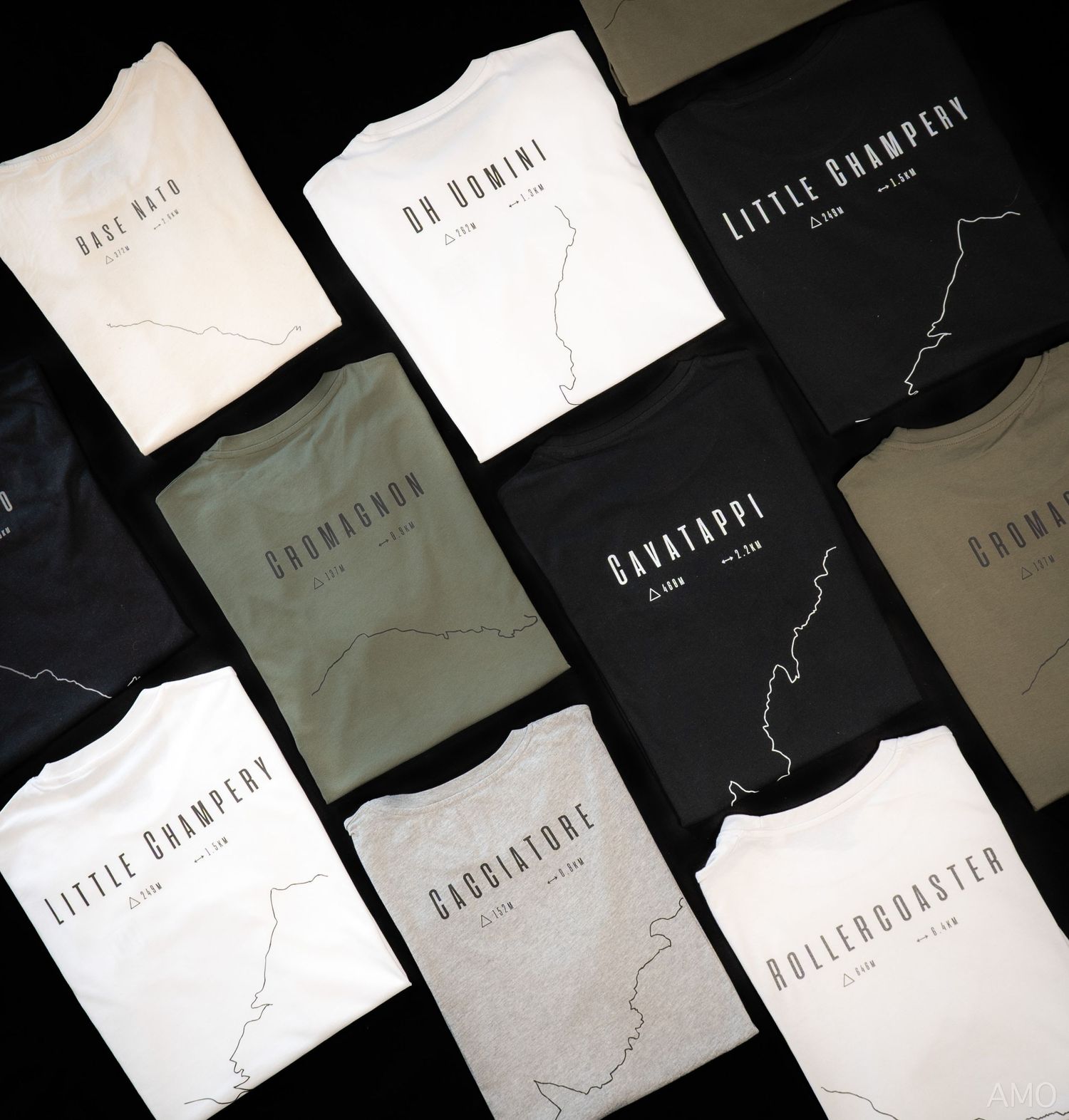 Collection of folded t-shirts in black, white, and earth tones featuring minimal graphic designs.