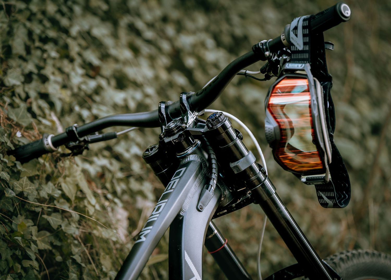 Close-up view of bicycle handlebars with water bottle holder mounted against blurred rock wall background.