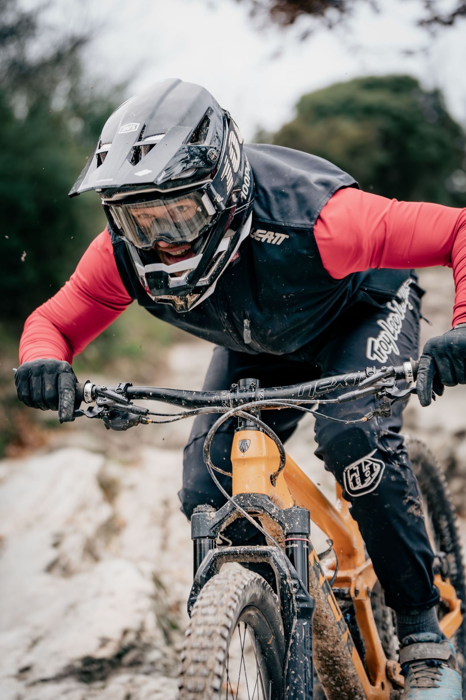 Mountain biker in protective gear riding on rough terrain with focused determination.