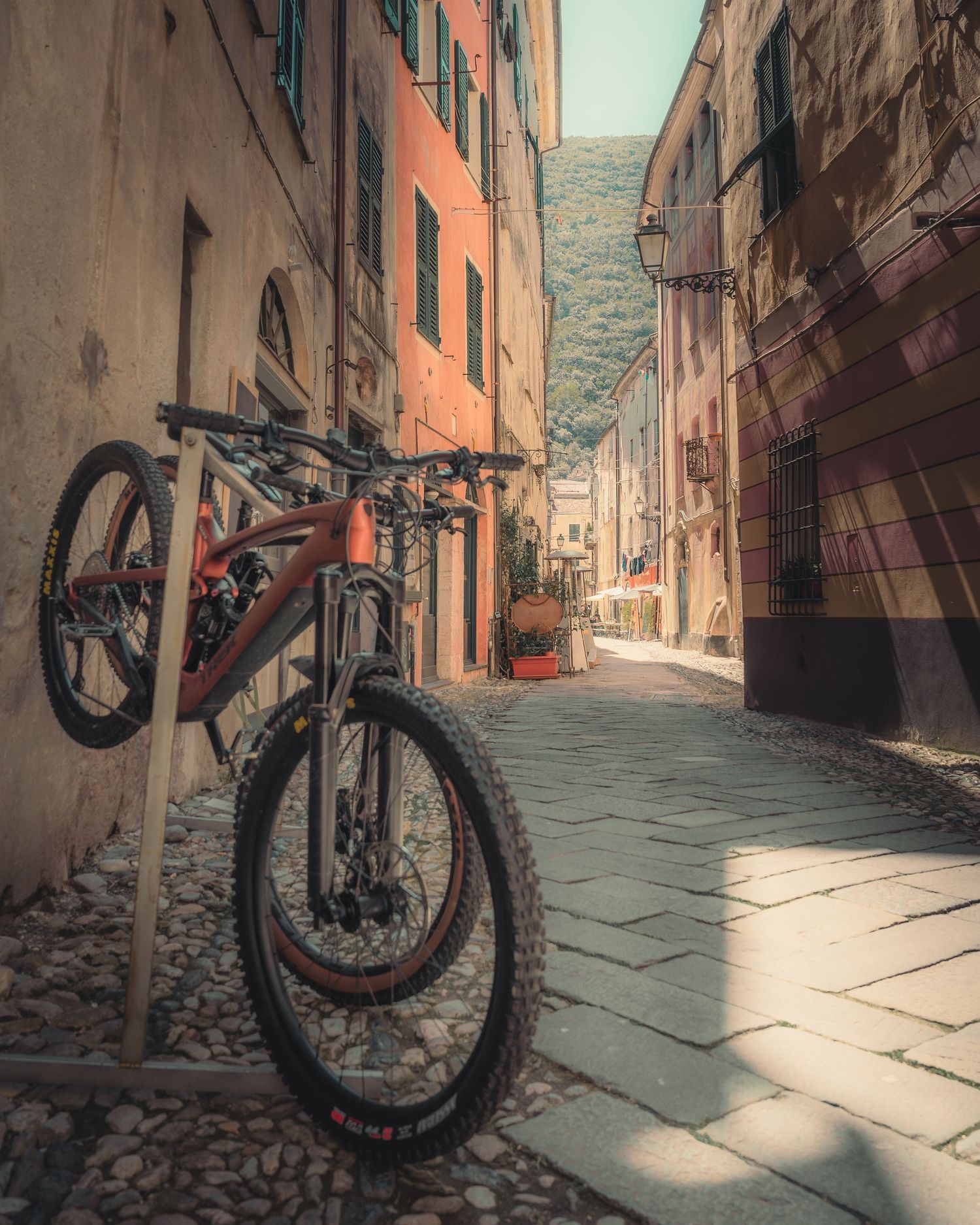 Mountain bike parked in a narrow European alleyway with colorful buildings and cobblestone streets.