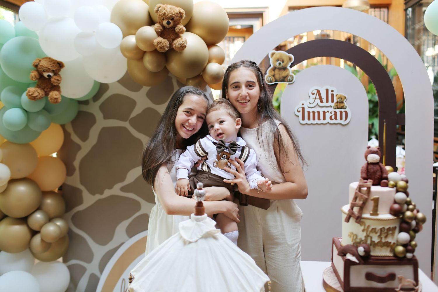 Elegant baby celebration with balloon arch decorations and teddy bear theme.