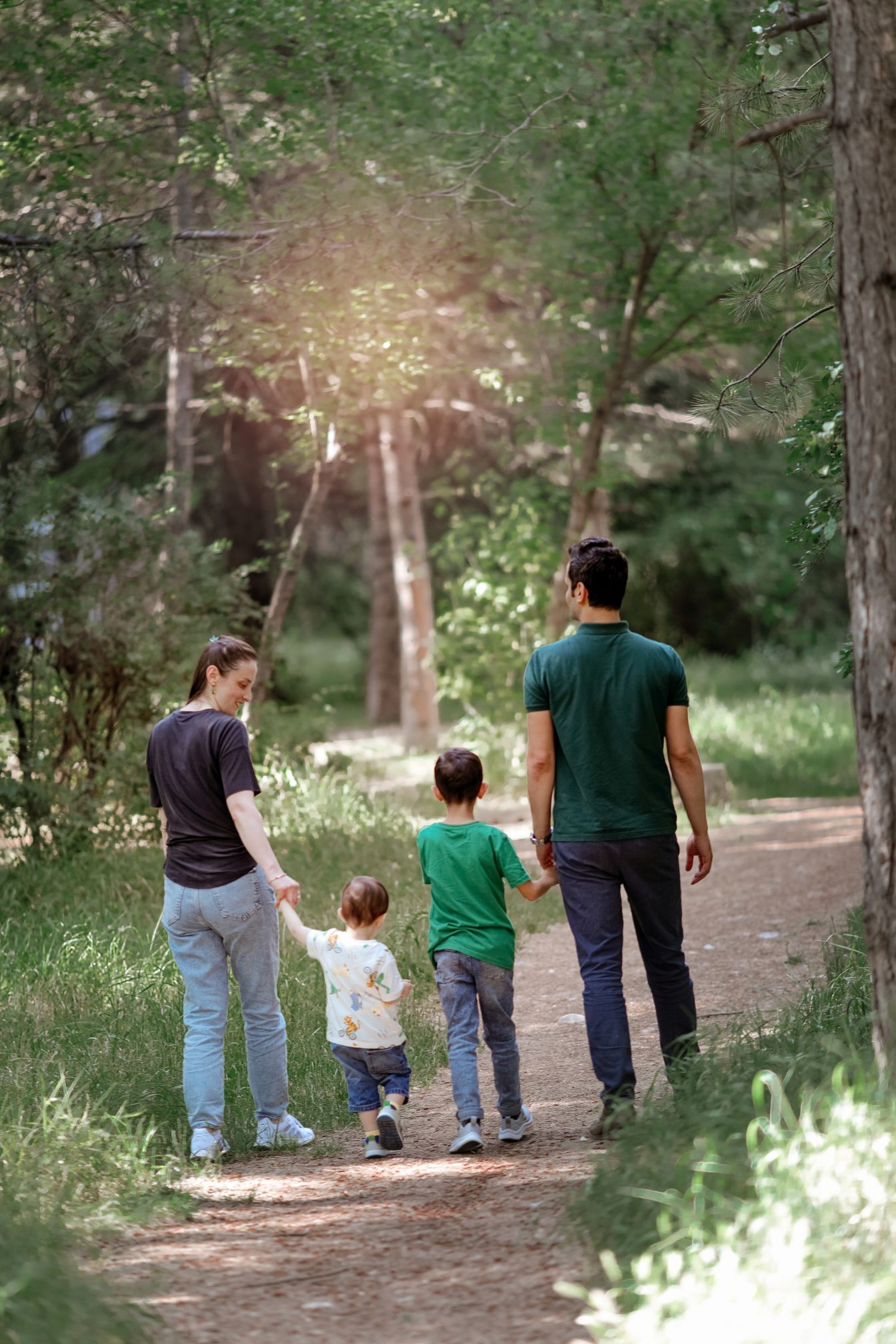 A family taking a nature walk together on a sunlit forest trail.