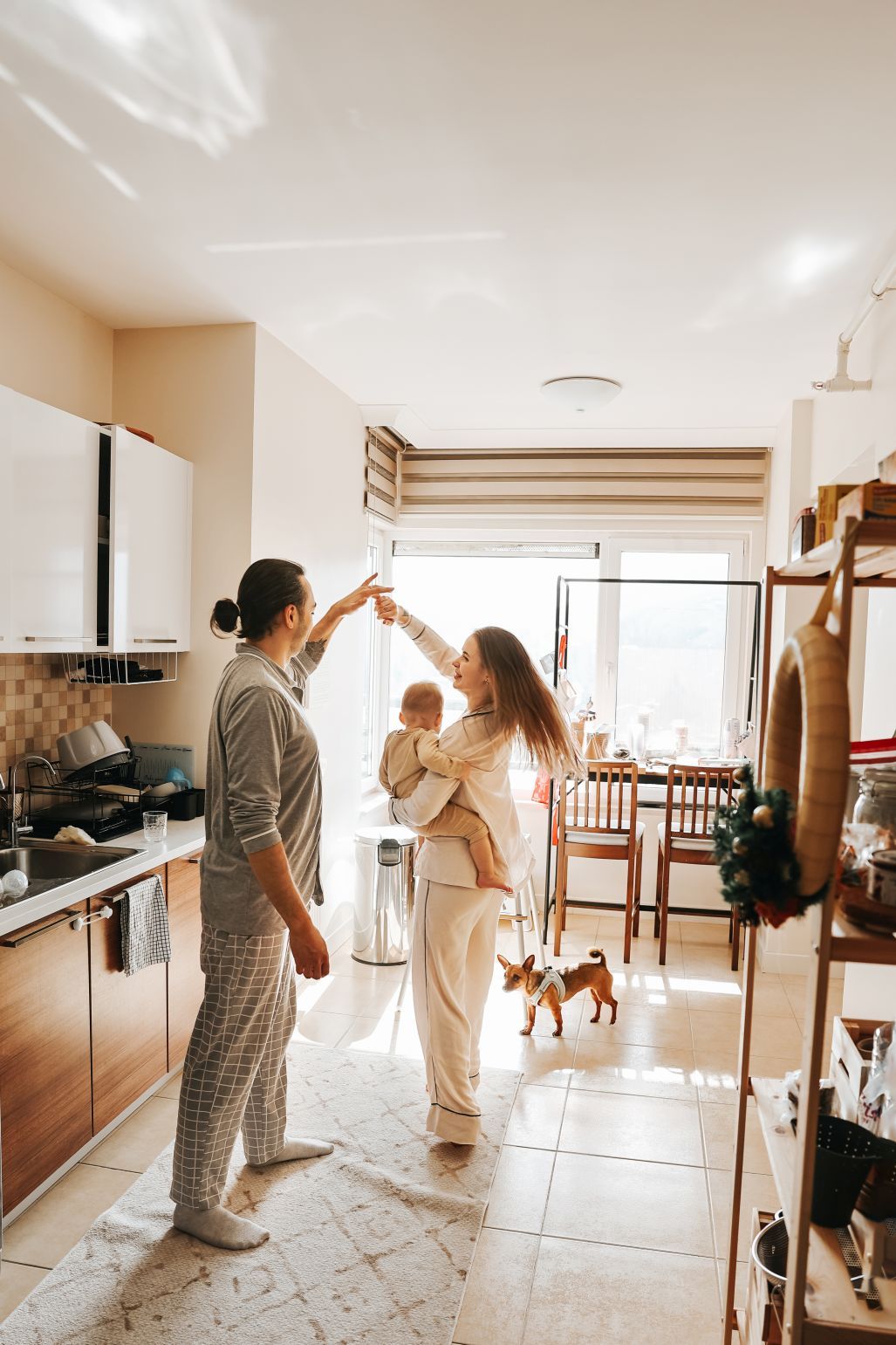 A cozy kitchen scene with a small dog watching people share an intimate domestic moment.