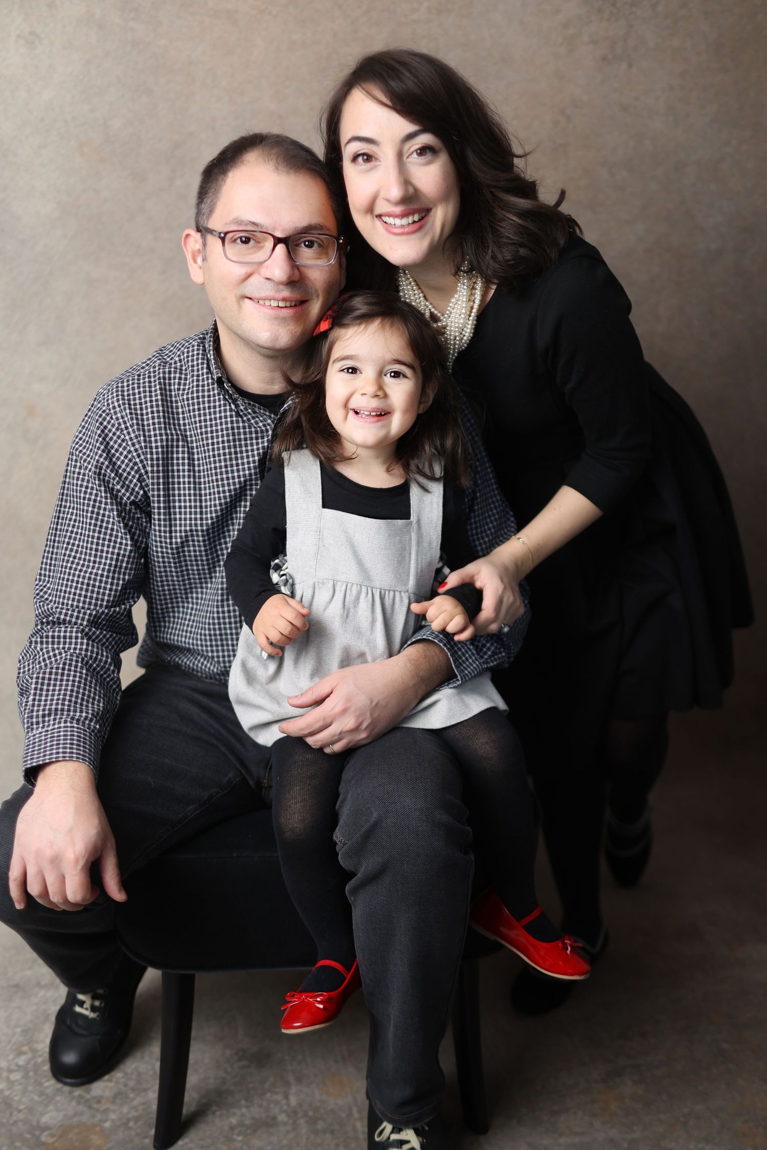 Studio family portrait with neutral background and classic styling.