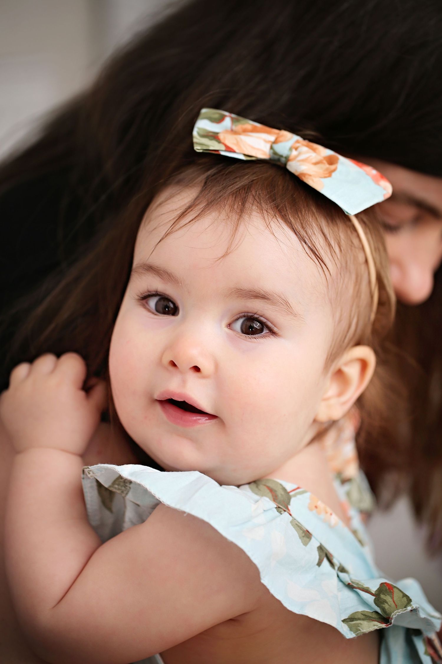 Baby wearing floral bow headband and light blue outfit.