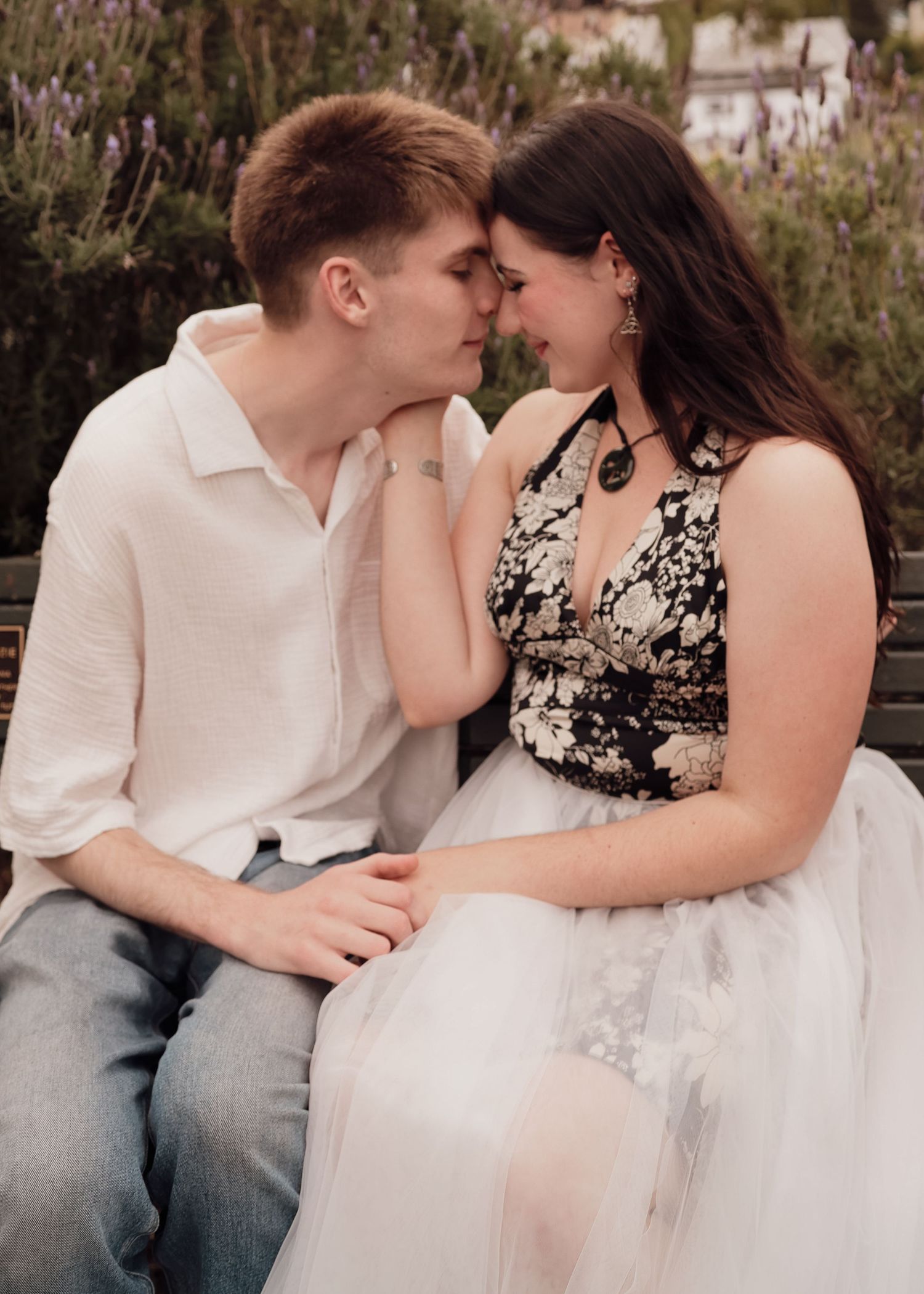 Young couple shares a tender romantic moment sitting close together in a garden setting.
