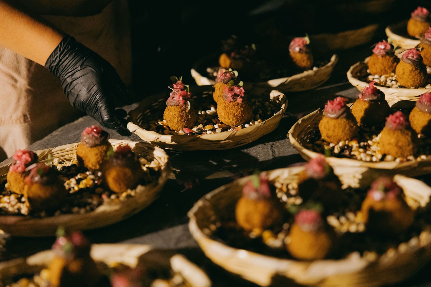 Elegant chocolate truffles with pink garnishes displayed on rustic wooden plates at a catered event.