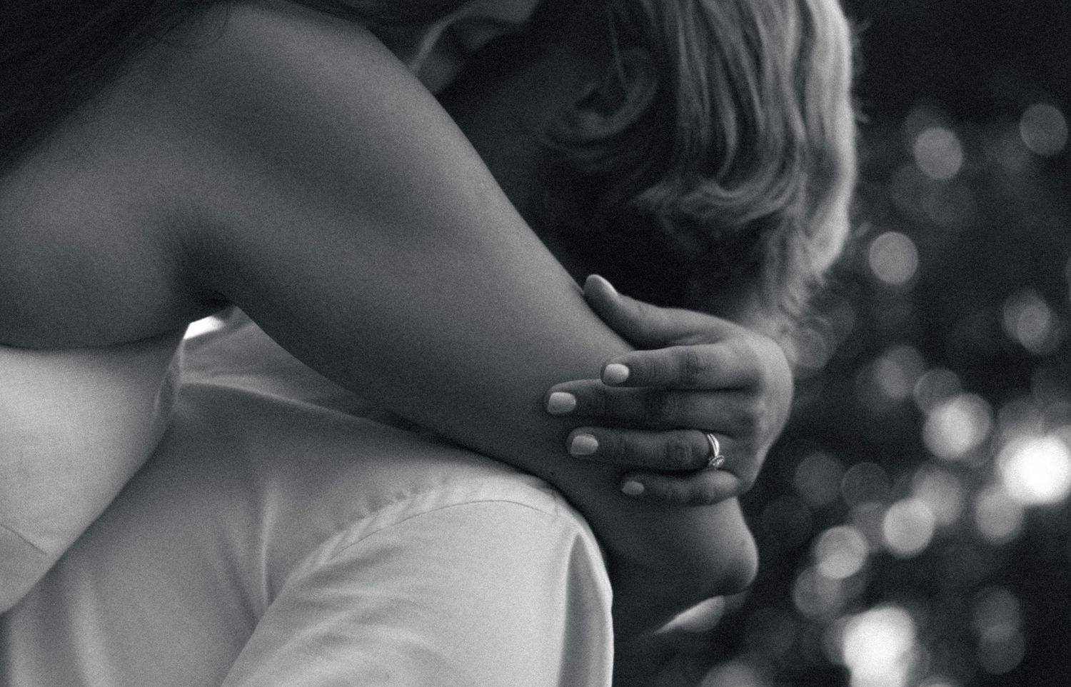 Black and white photo of two people sharing a tender embrace, with a hand gently resting on a shoulder.