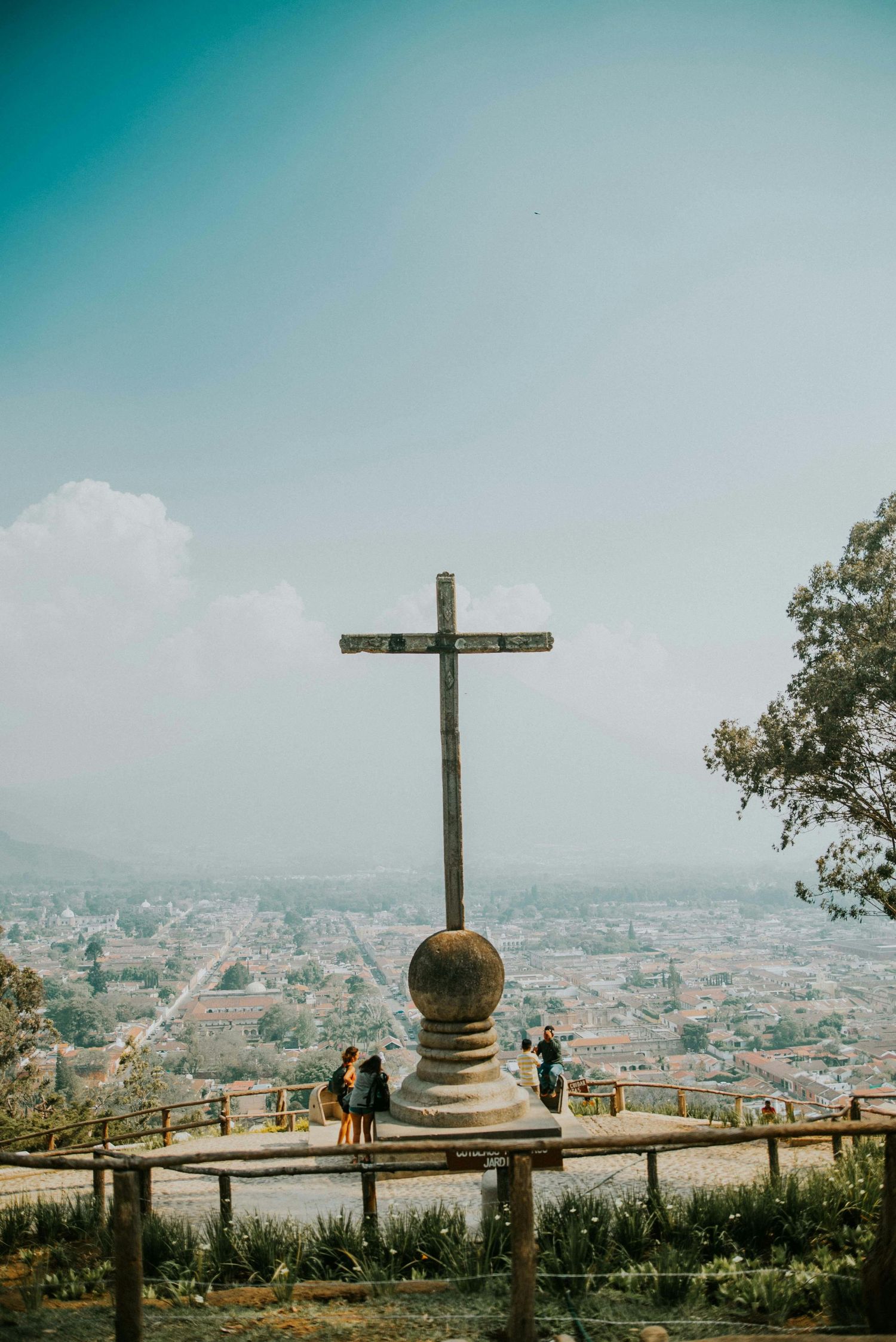 A large stone cross monument atop Cerro de la Cruz overlooks the colorful cityscape of Antigua, Guatemala.