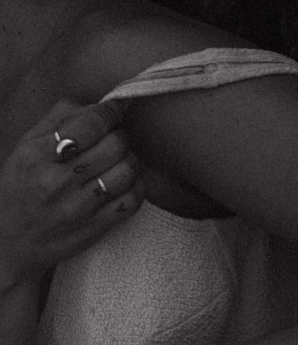 Close-up black and white photo of a hand with rings pulling at white fabric waistband.